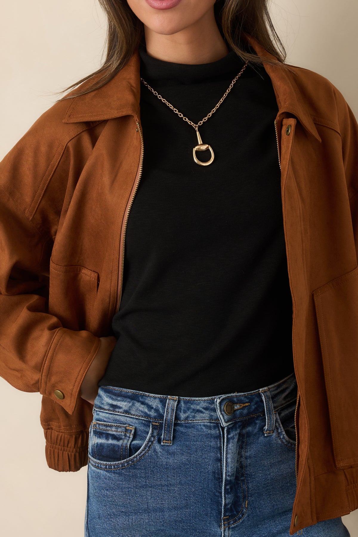 Close view of the cognac faux suede texture, pointed collar, zipper, and snap cuff detailing.