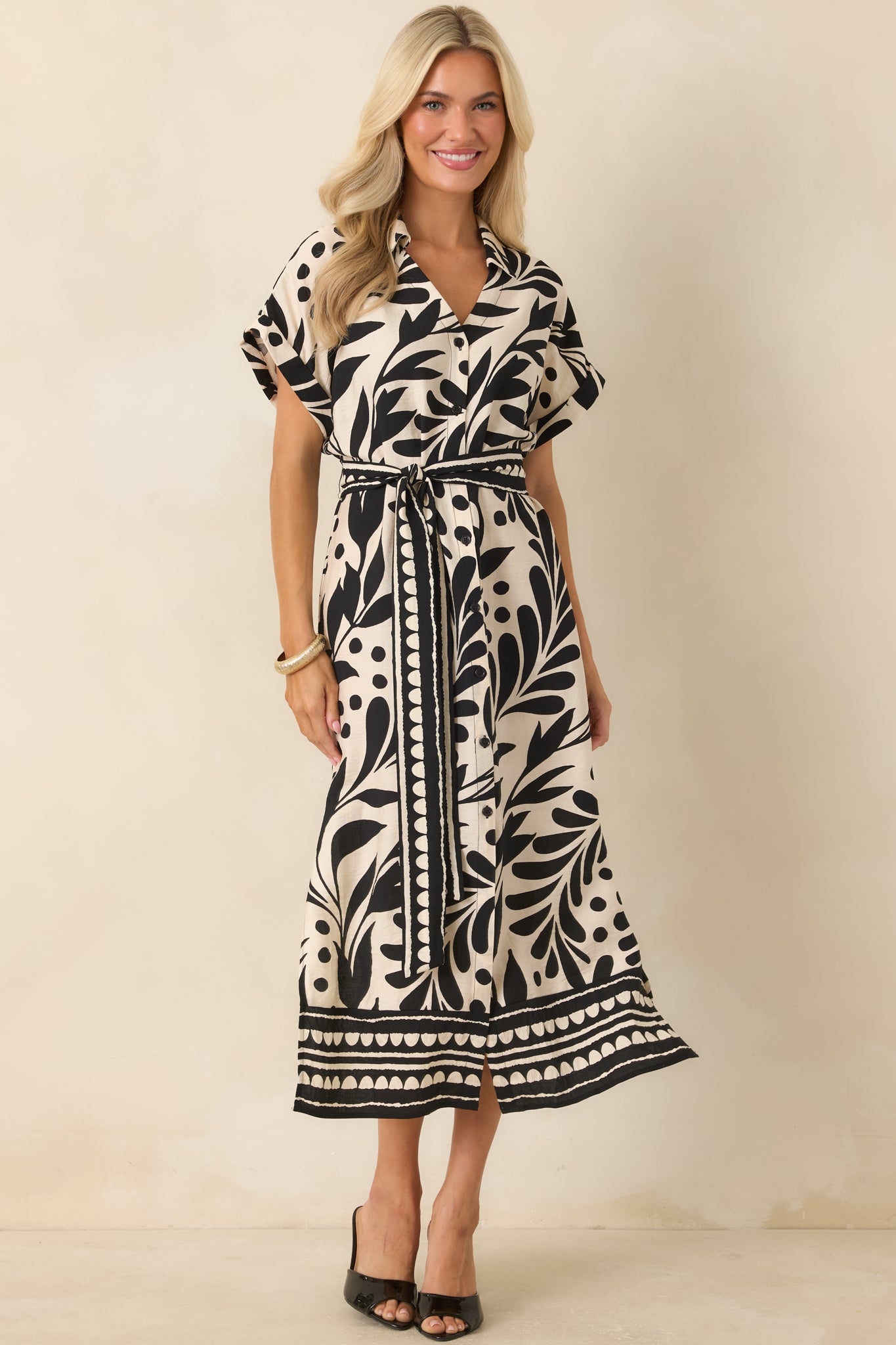 Elegant botanical midi dress with a collared neckline, coordinating hem border details, adjustable waist tie, and flowing shape.