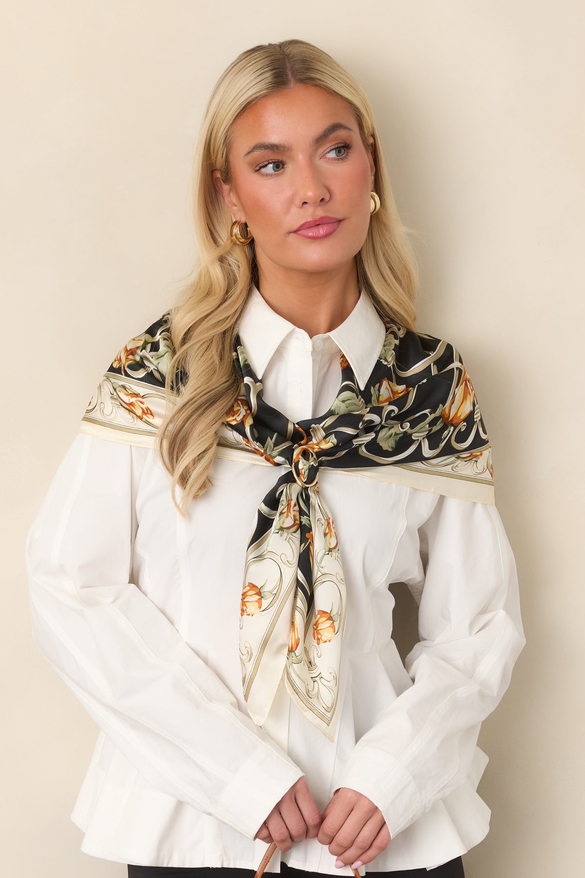 Collared cotton top featuring long sleeves, polished buttons, a defined waist, and structured peplum shaping.