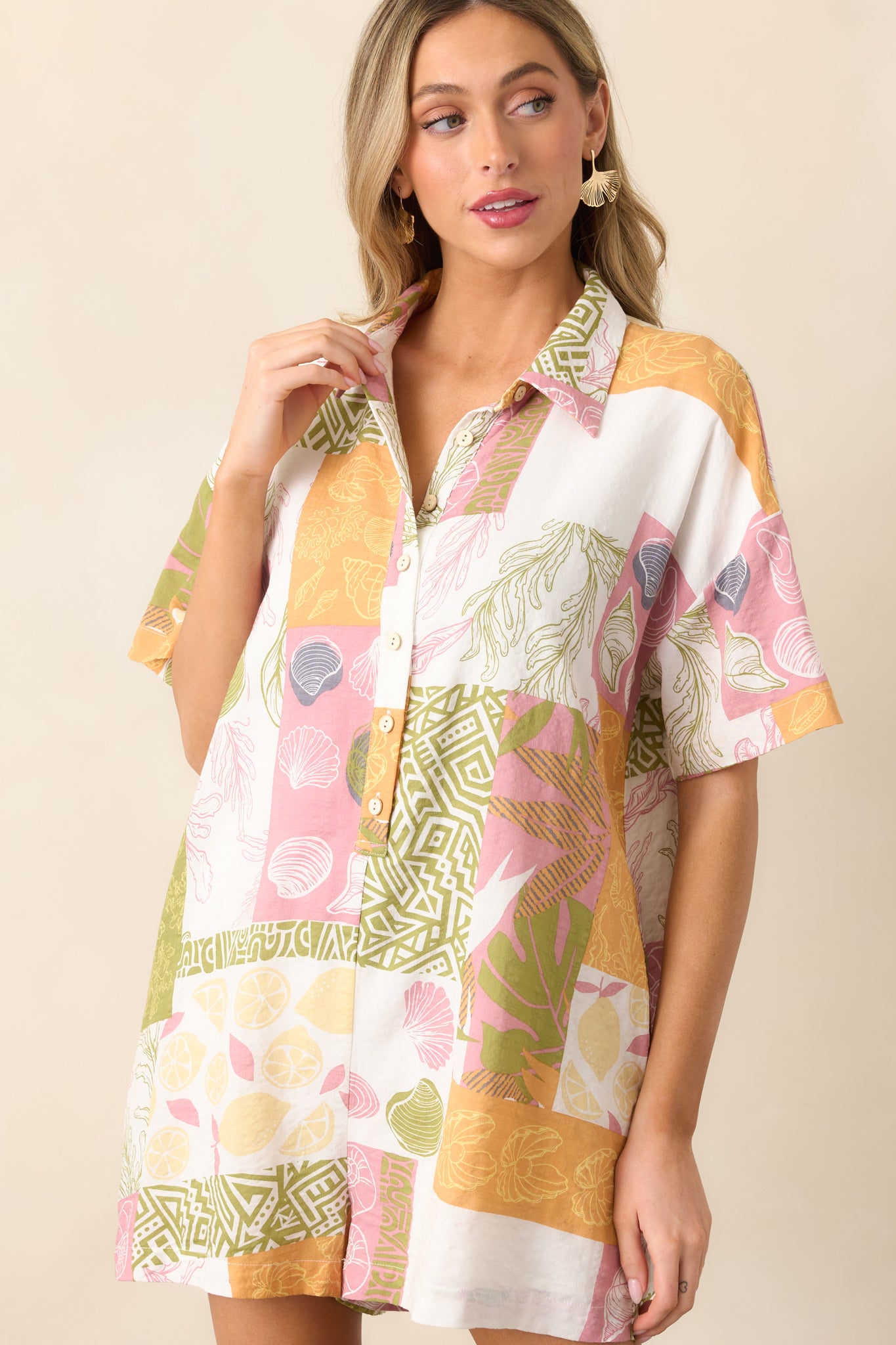 A detailed look at the short-sleeve romper’s collared neckline and button closures, emphasizing the contrast between the ivory fabric and the vibrant patchwork print.
