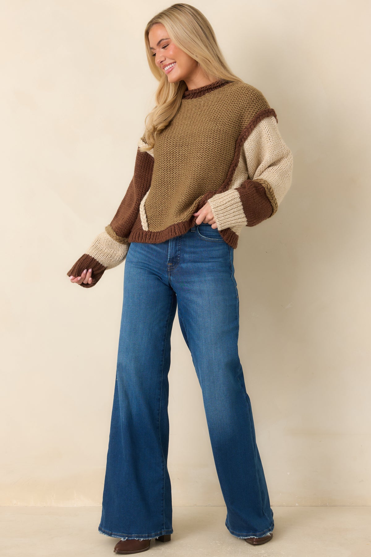 Chunky color-block knit pullover with contrasting textures, raised braided seams, and a chocolate brown ribbed crew neckline.