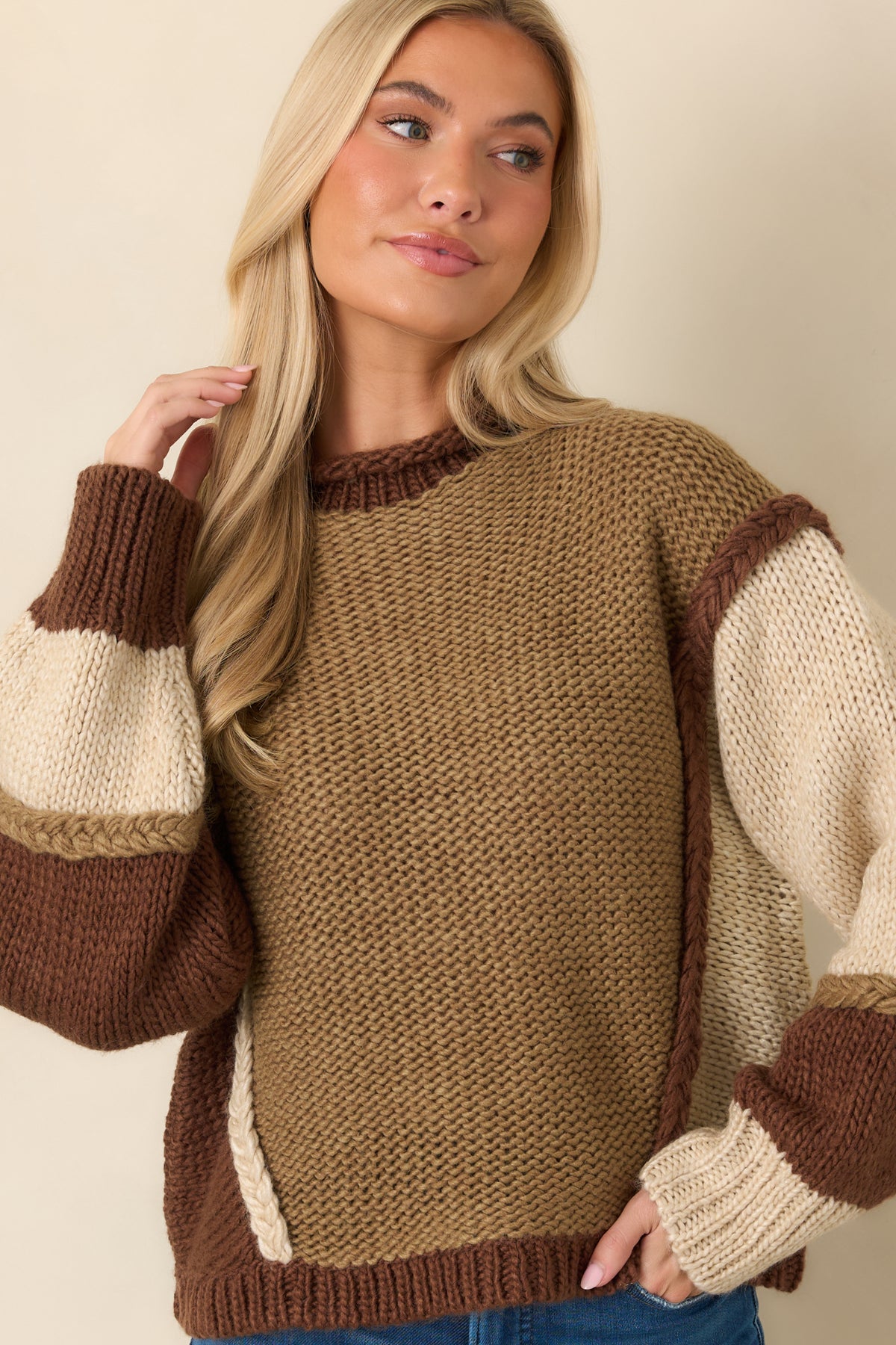 Raised braided seams separate the asymmetrical color-block sections across the sweater's front.
