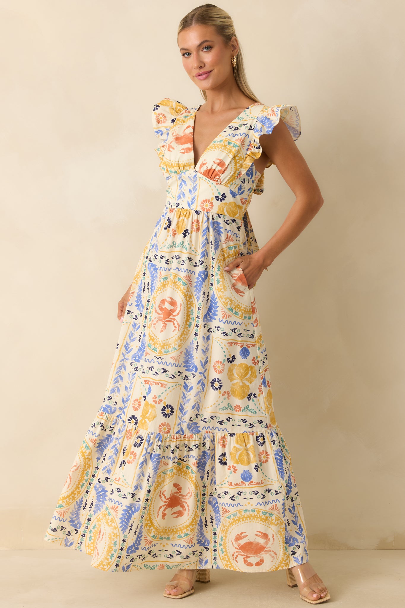 Colorful patchwork maxi dress featuring a V-neckline, ruffled cap sleeves, fitted bodice, and a flowing tiered skirt with Mediterranean-inspired prints.