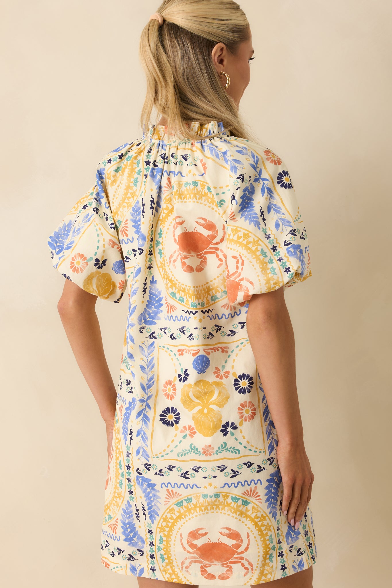 Rear view of the colorful cotton mini dress highlighting the relaxed shift silhouette, puff sleeves, and vibrant patchwork print.