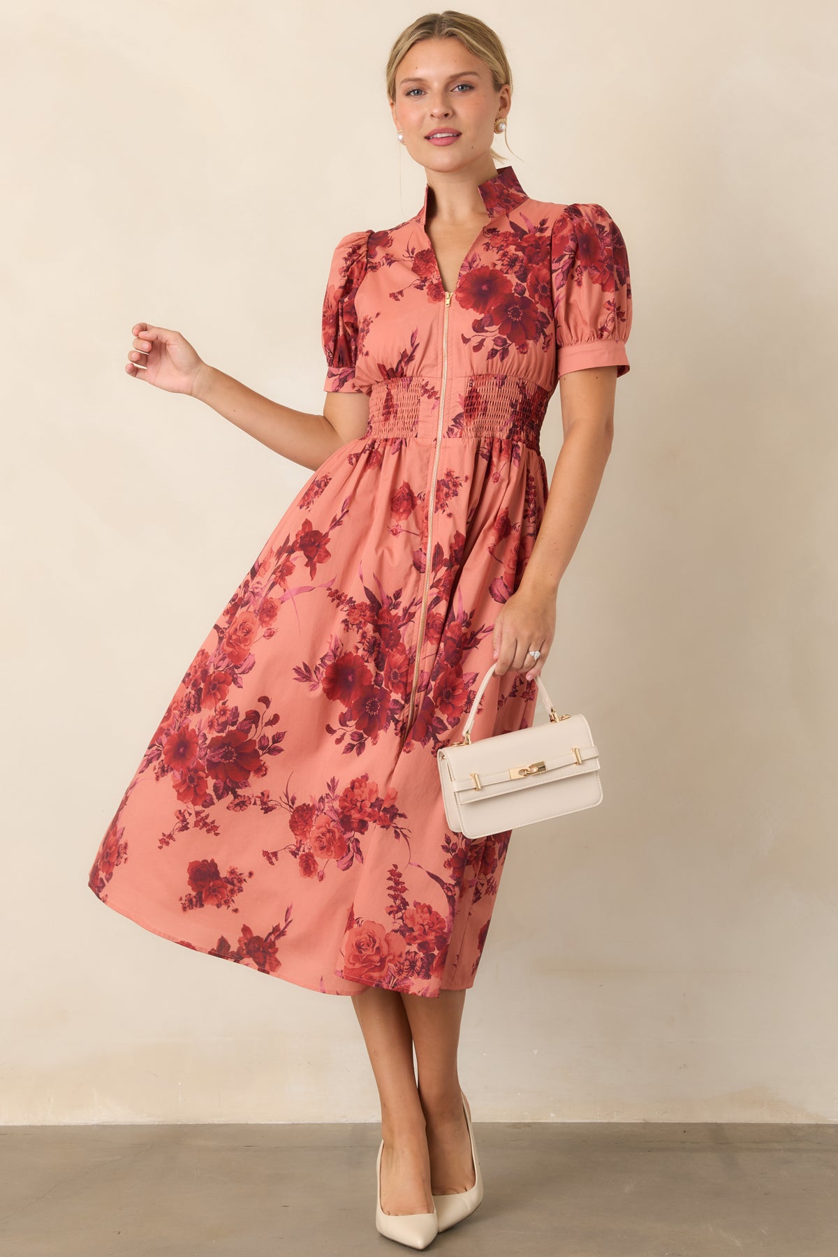 Warm coral midi dress defined by burgundy floral motifs, structured collar, and polished front zipper.