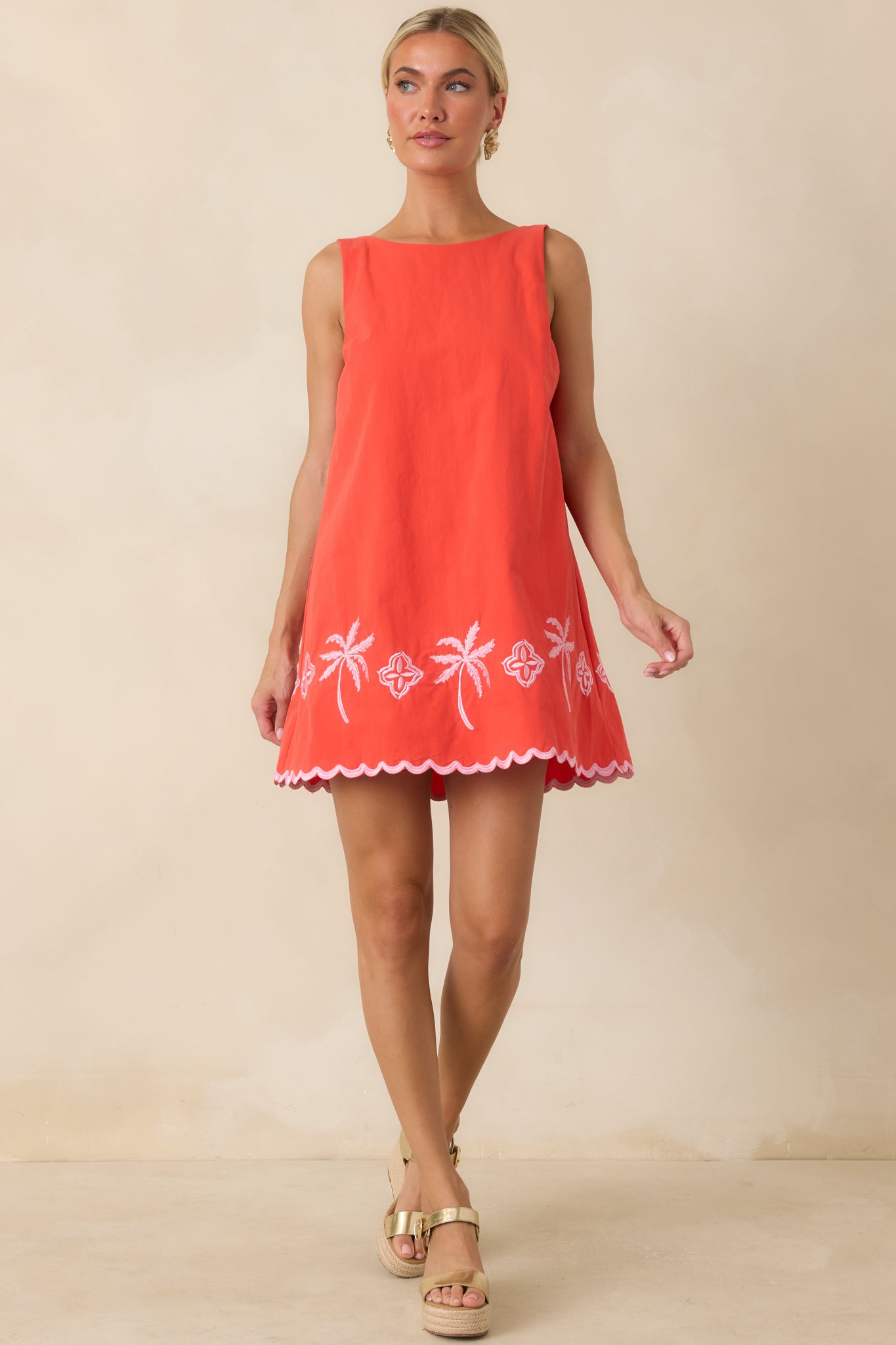Vibrant coral mini dress with playful pink embroidery, coastal-inspired palm trees, and an easy pull-on silhouette.