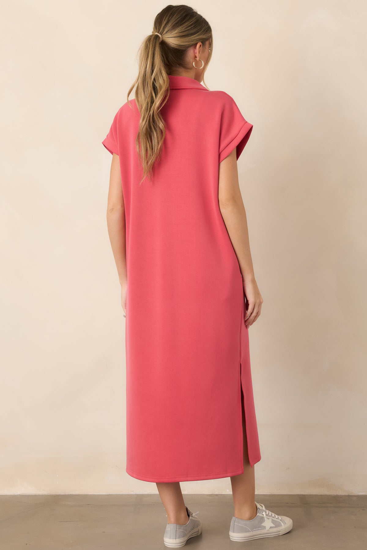 Rear view of the coral pink midi dress showcasing its relaxed fit, short sleeves, smooth fabric, and side vent detailing.