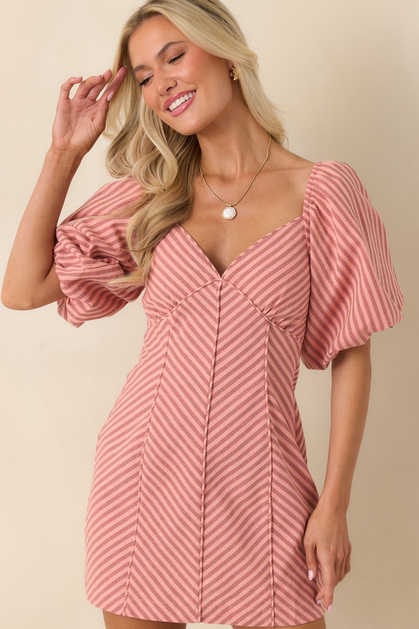 Close crop of coral pink stripe mini dress highlighting the sweetheart neckline and puff sleeve detail.