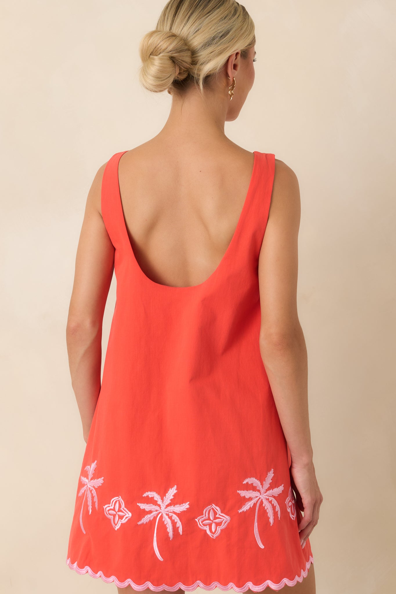 Back of the coral red cotton mini dress featuring a relaxed pull-on silhouette and clean embroidered details.