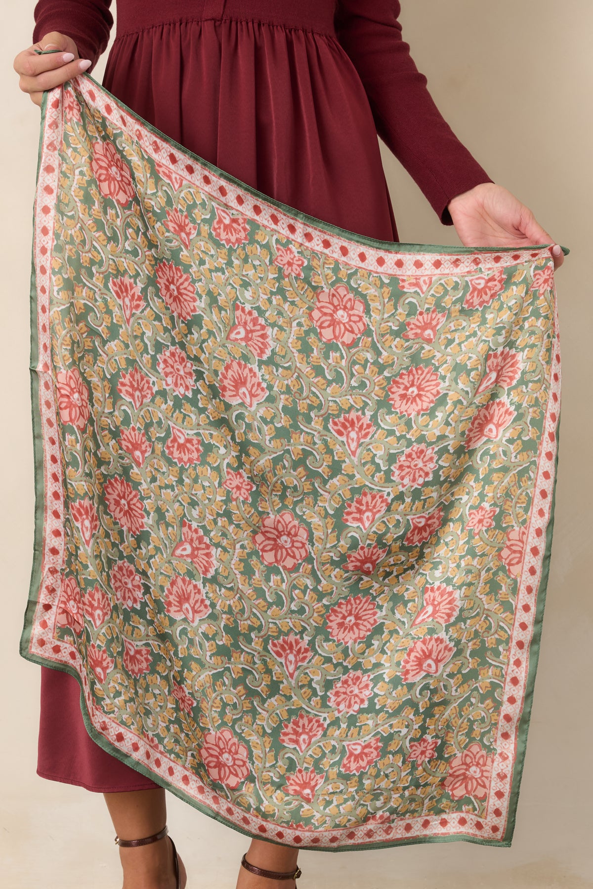 Scarf showcasing coral and rust flowers with golden yellow accents against a muted green background.