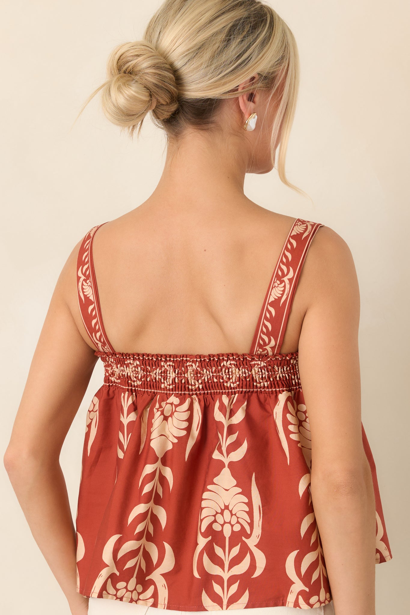 Rear view of the cotton babydoll top featuring a smocked elastic back and gathered silhouette for a flexible fit.