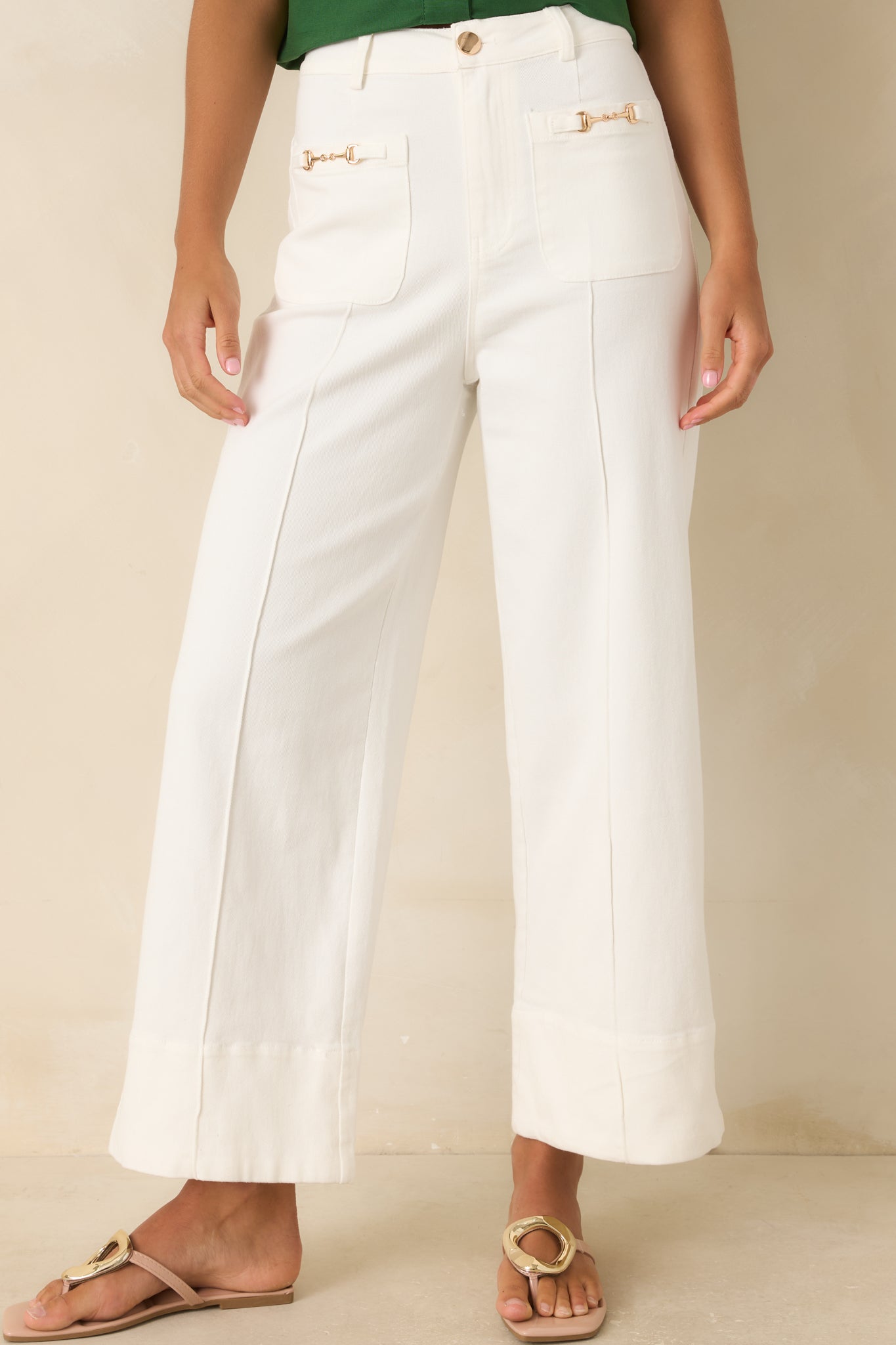 Cotton blend pants featuring crisp pleating, sleek patch pockets, and elevated gold-tone front accents.