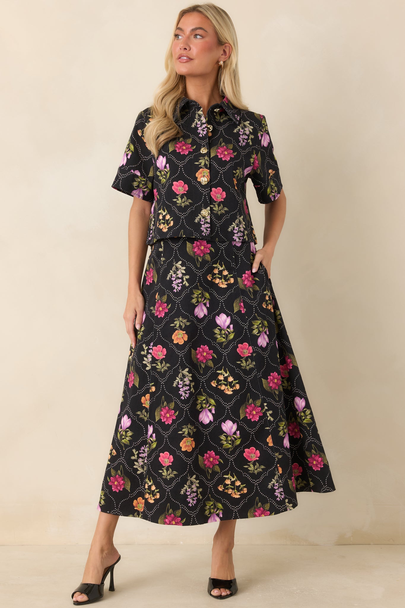 Cotton-blend top with a pointed collar, short sleeves, and a vibrant floral pattern on a black background.
