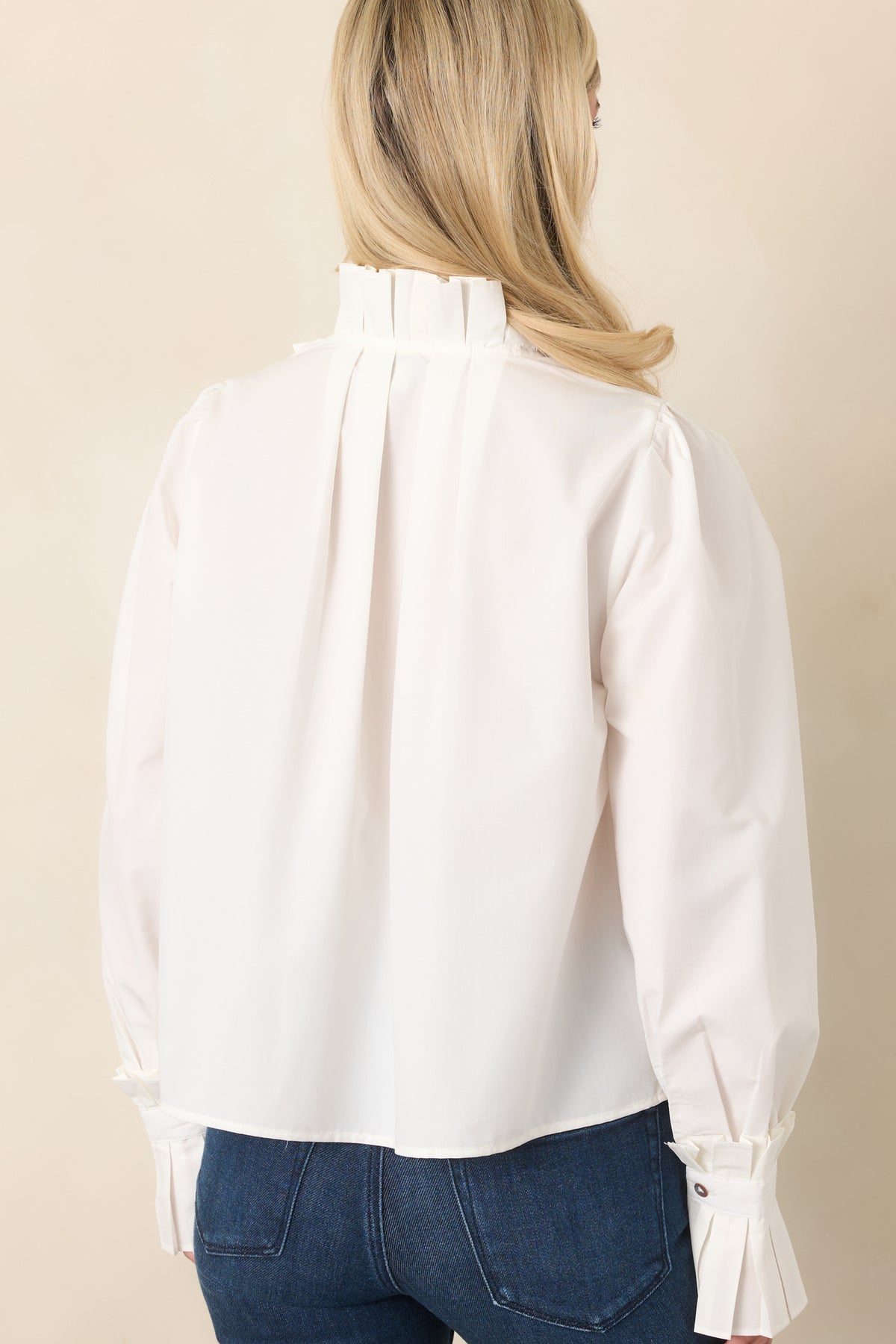 Rear view of the cotton blouse showcasing the back pleat, relaxed silhouette, and long sleeves.