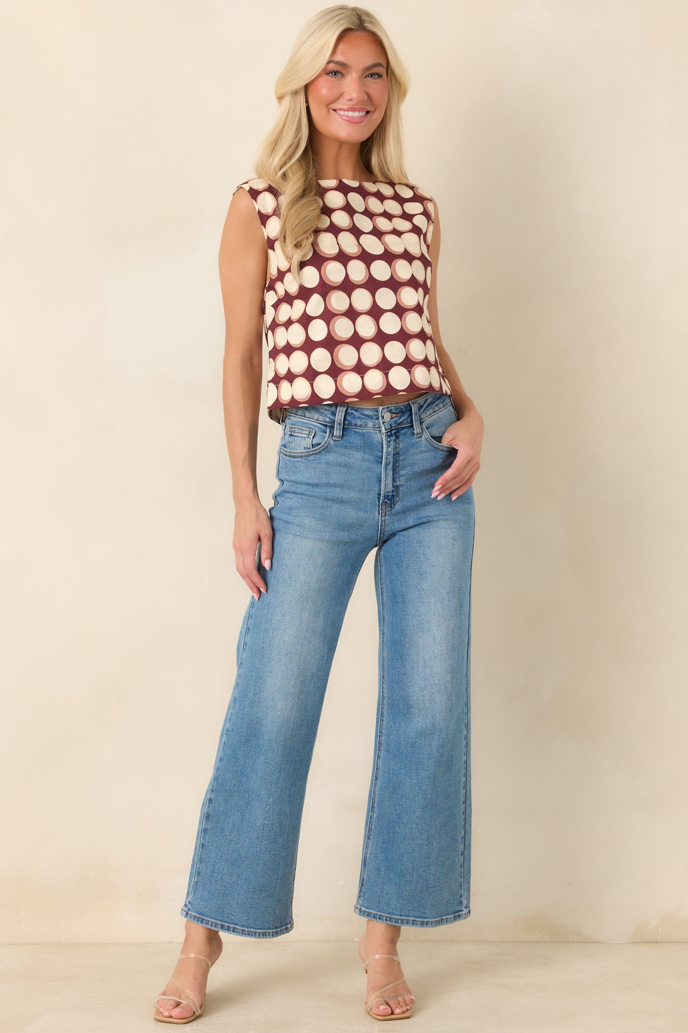 100% cotton top designed with a boat neckline, sleeveless cut, cropped length, and scattered abstract dots in ivory and muted tan.