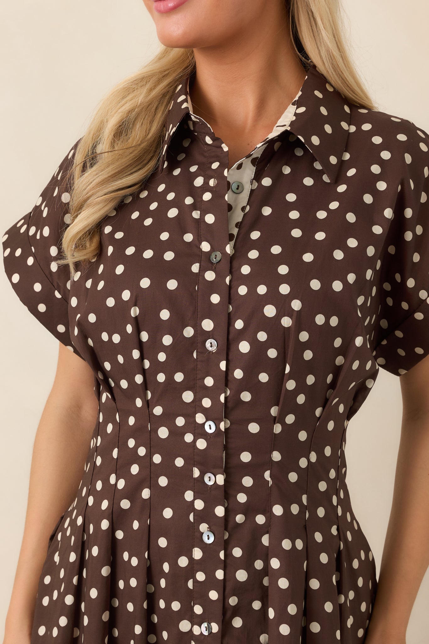 Close-up of the cotton dress highlighting the collared neckline, button front, and ivory contrast panel covered in brown polka dots.