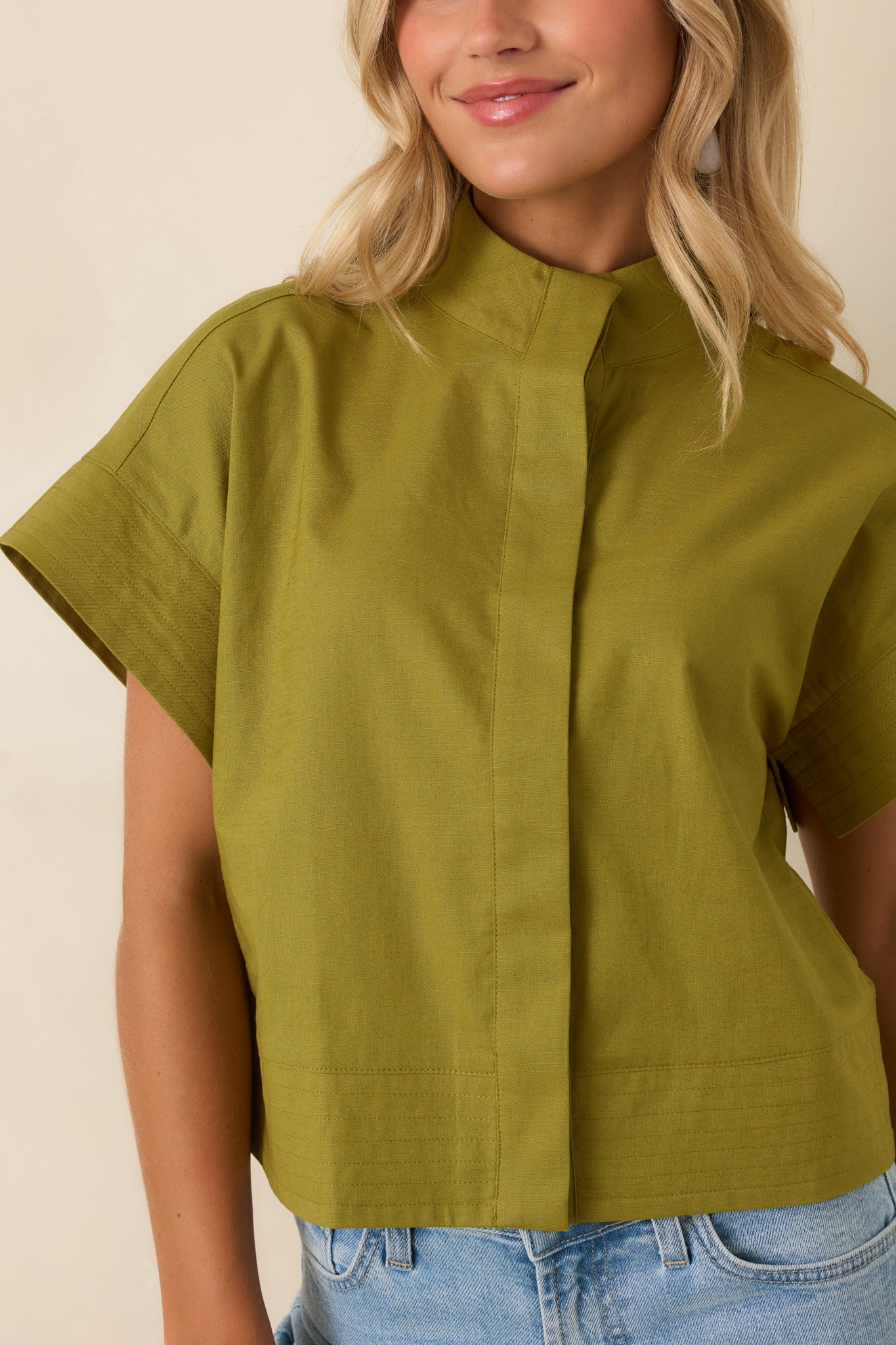 Detailed view of the cotton linen texture, concealed button-front placket, mock neckline, and refined hem stitching.