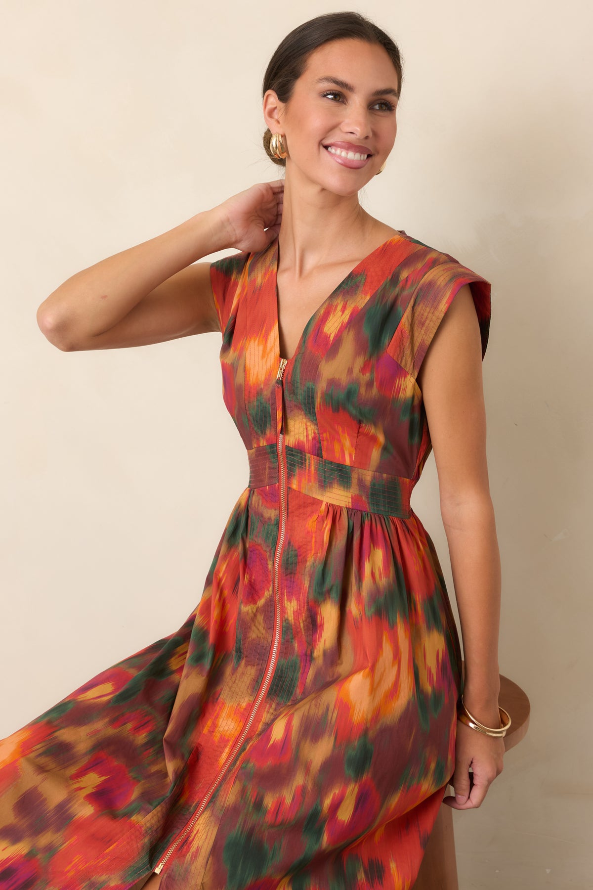 Close view of the cotton midi dress showcasing painterly floral colors, a defined waist, and front zipper.