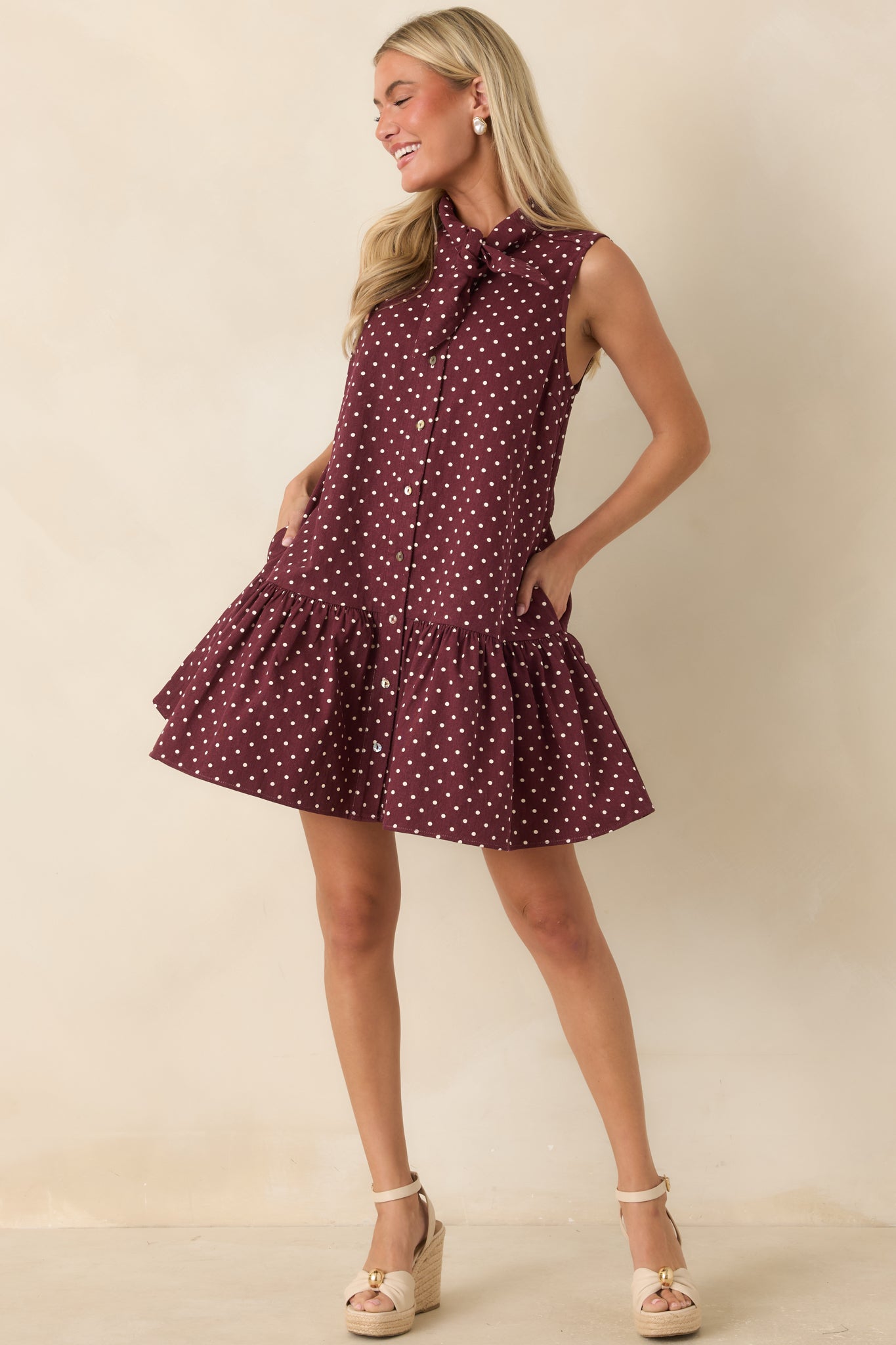 Cotton mini dress featuring ivory polka dots, a self-tie neckline, functional button-front closure, and a relaxed drop-waist silhouette.