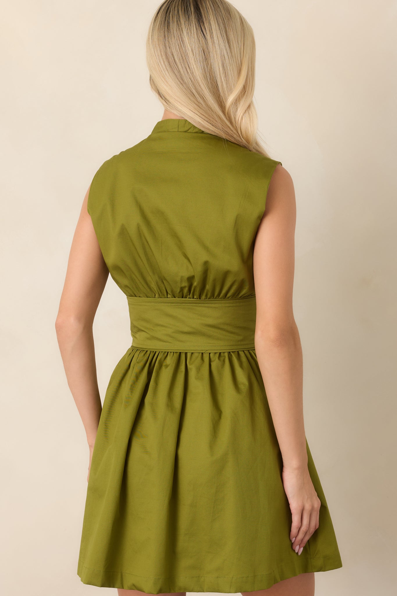 Rear view of the cotton mini dress highlighting its sleeveless silhouette, gathered waist, softly flared skirt, and clean cotton lining.