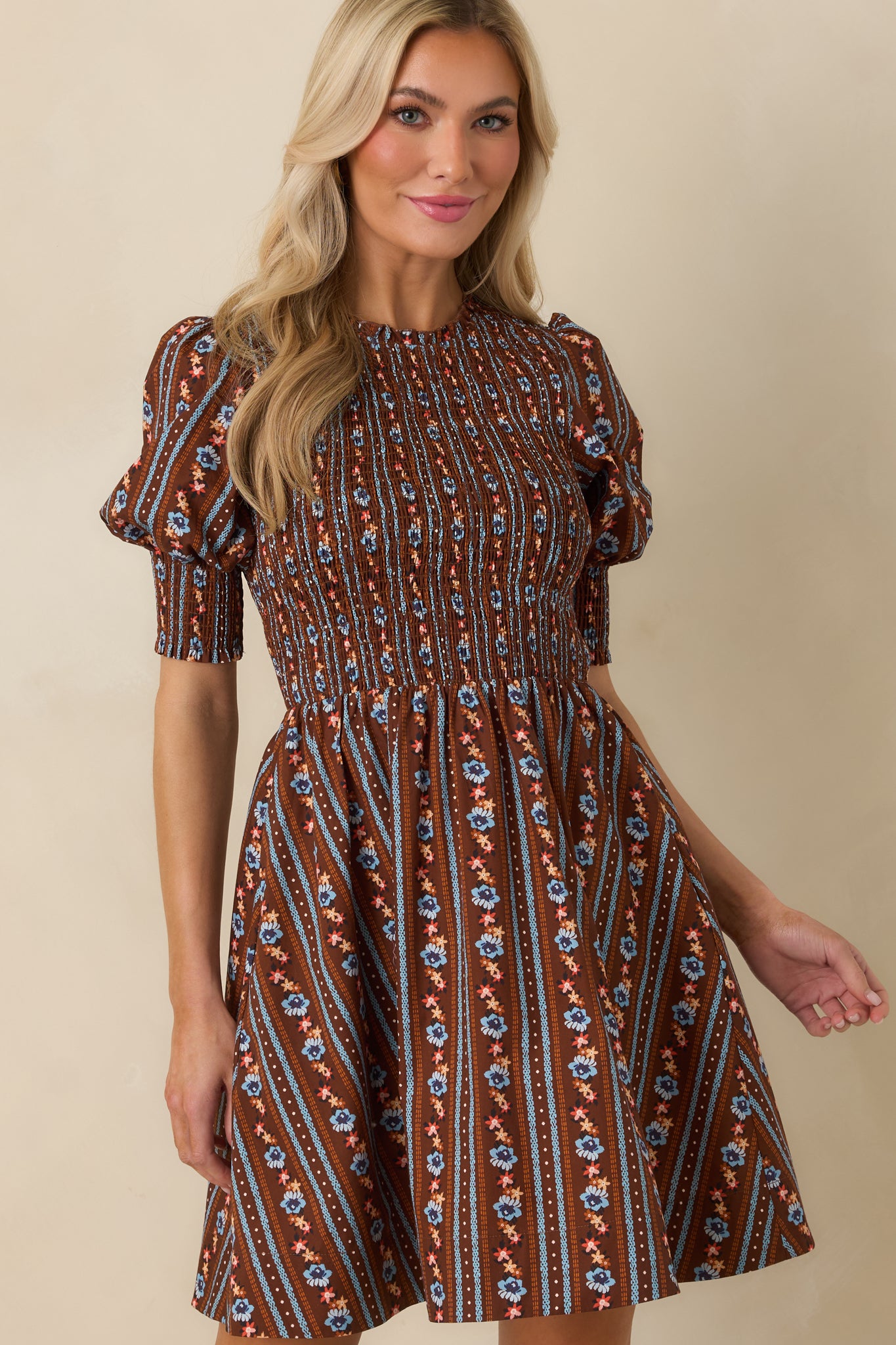 Cotton mini dress featuring wide smocked cuffs, softly gathered puff sleeves, and a rich brown floral print.