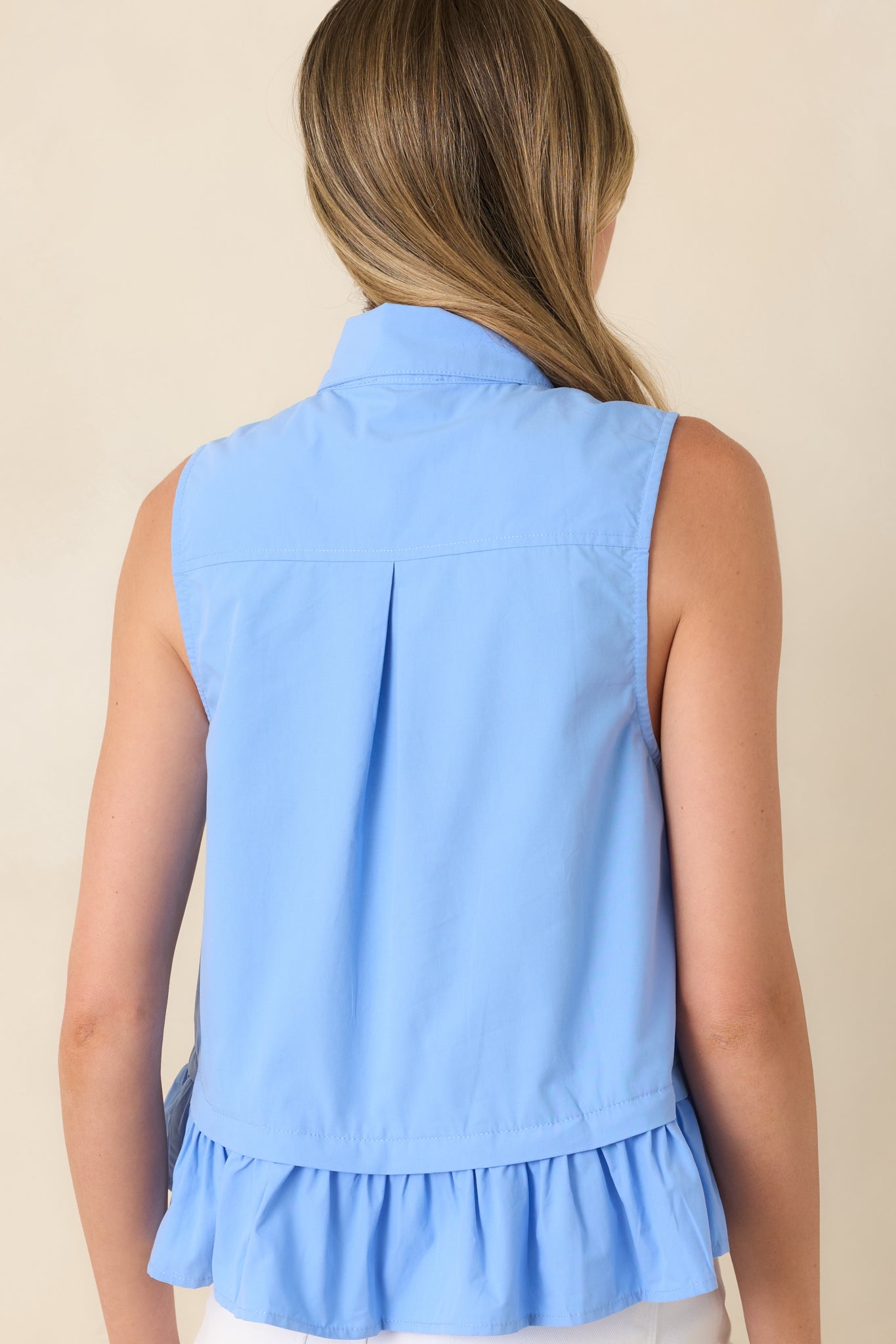 Rear view of the cotton sleeveless top highlighting the relaxed shape, gathered ruffle hem, and clean back silhouette.