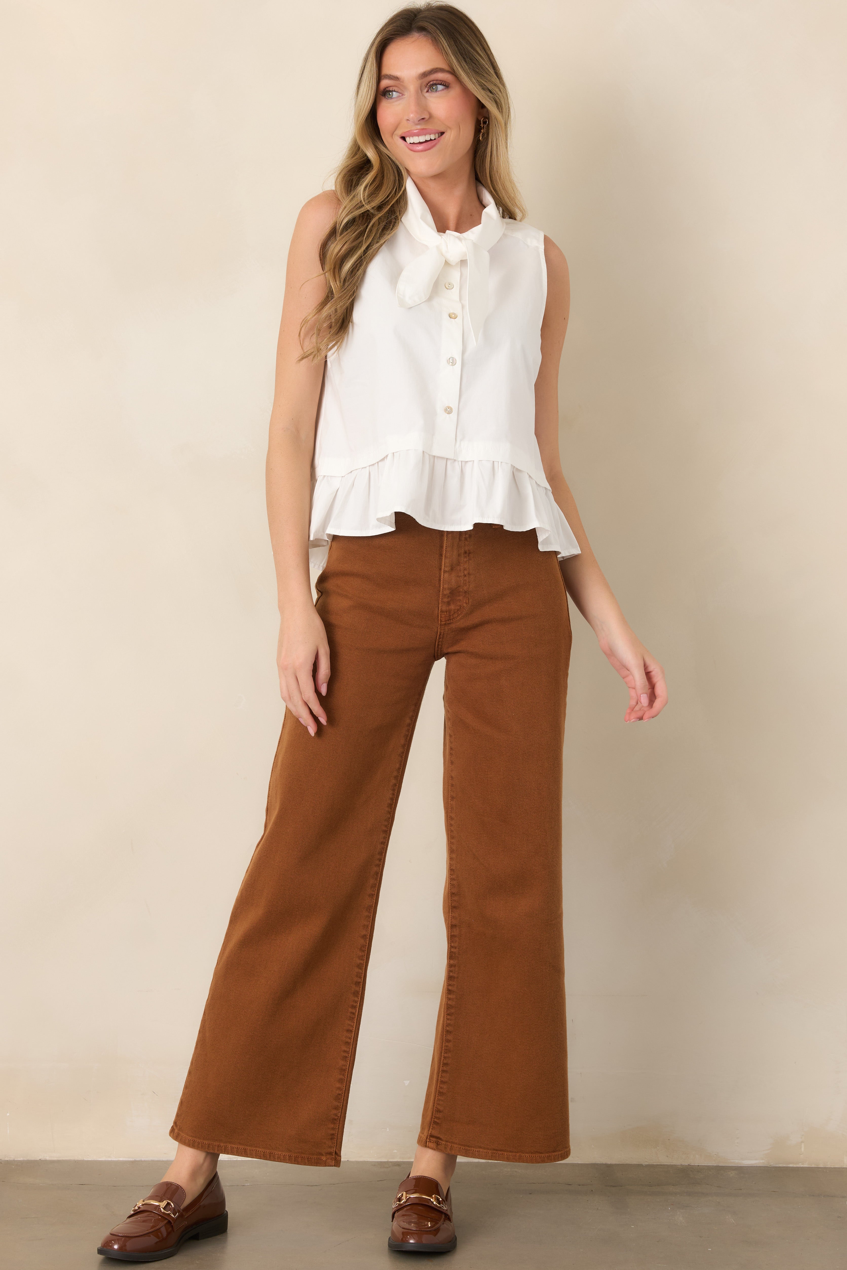 Breathable cotton sleeveless top with a softly tied neckline, button-down front, and gently gathered ruffle hem that adds movement.