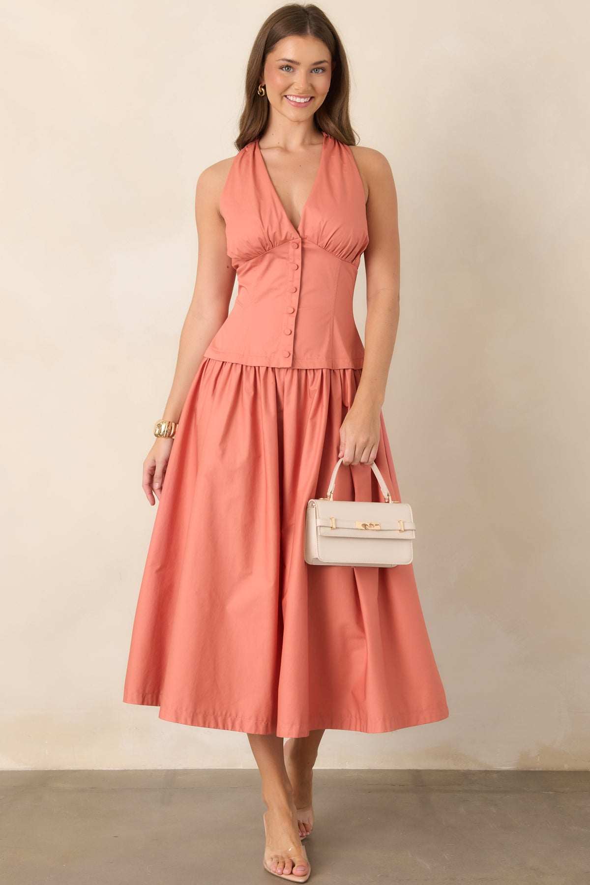 Sleeveless cotton midi dress featuring a structured V-neck bodice, functional button detailing, and a flowing skirt with soft movement.