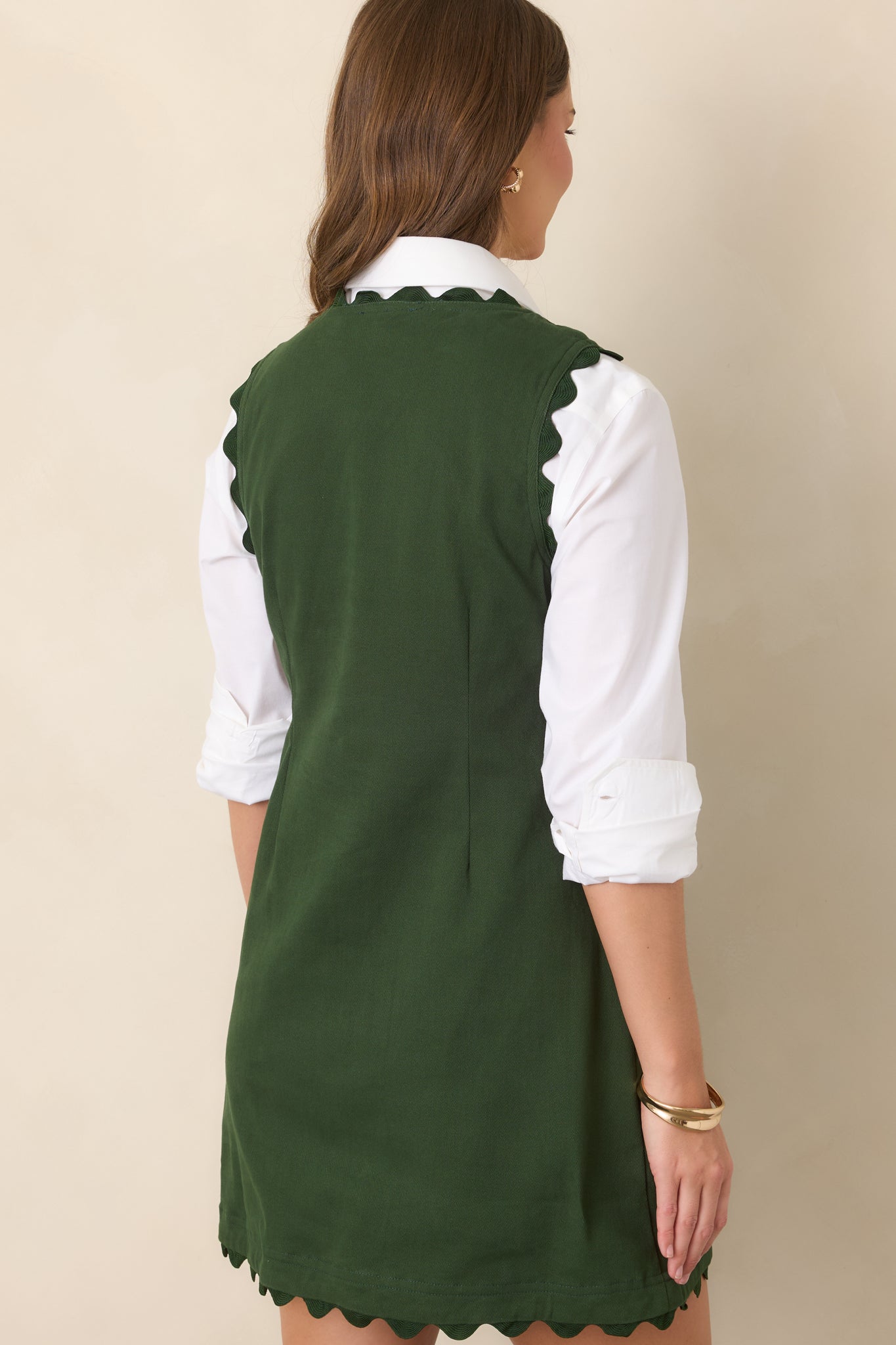 Rear view of the cotton-rich stretch mini dress highlighting its shaped waist, sleeveless silhouette, tonal ric rac hem trim, and clean finish.