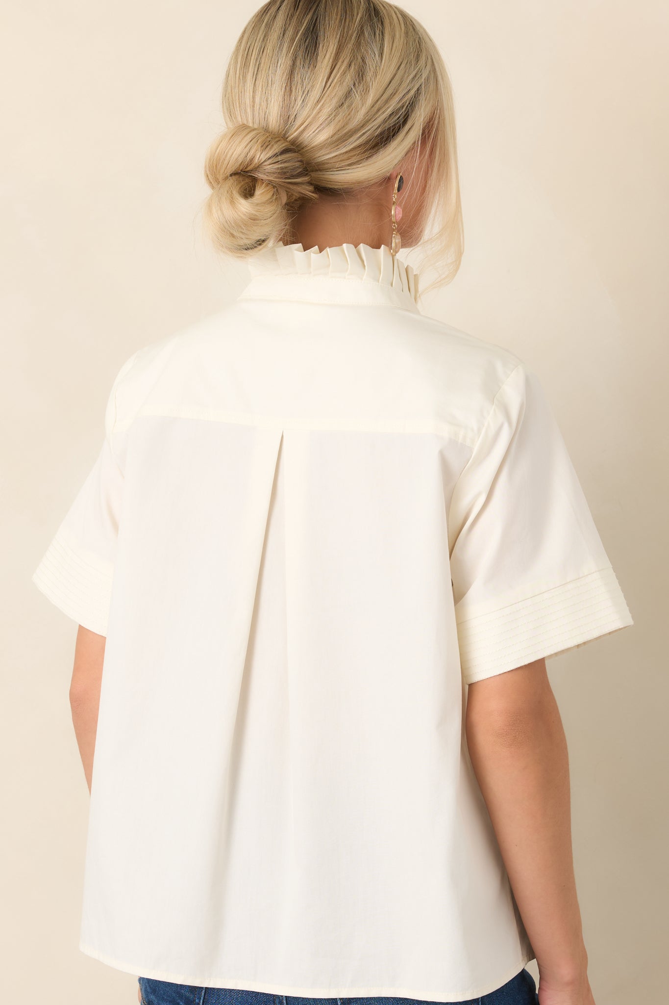 Rear view of the cotton top showing the center back pleat, relaxed drape, short sleeves, and clean hemline.