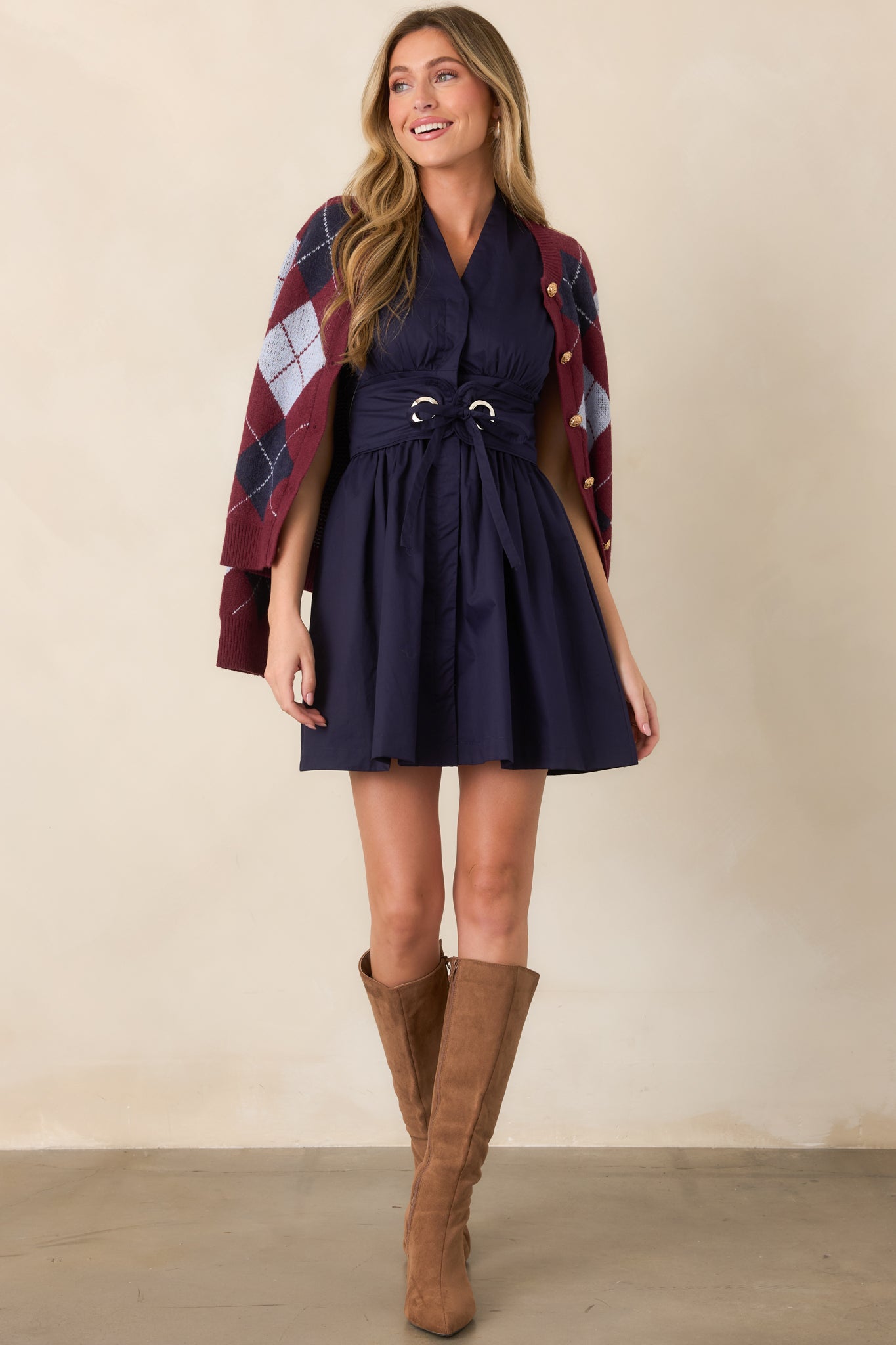 Cotton mini dress featuring a sleeveless V-neckline, concealed front button placket, gathered waist, softly flared skirt, and removable wide belt with metal grommets.