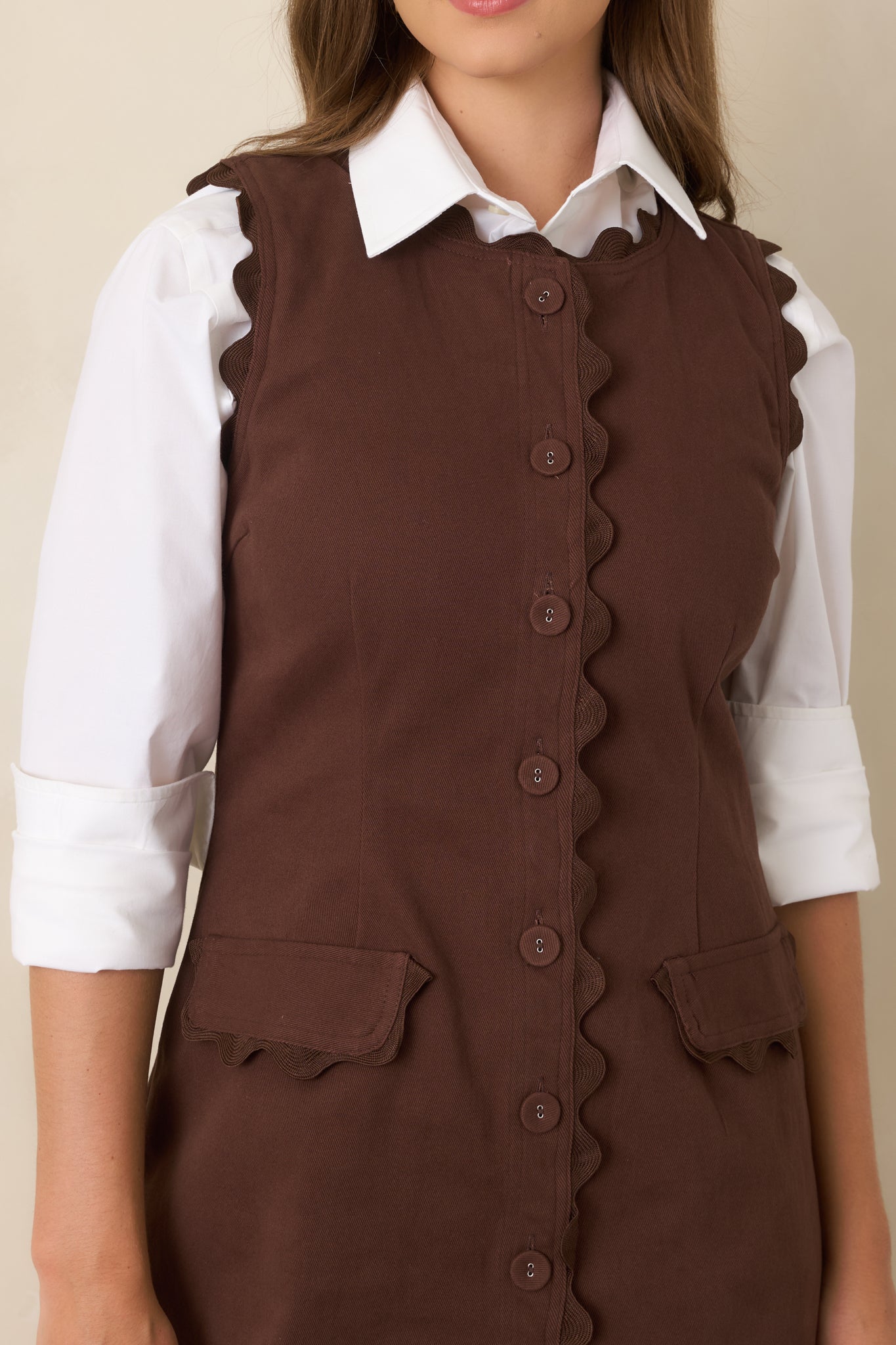 Close-up highlights the covered buttons, tonal ric rac trim, and petite flap pocket detailing across the front.