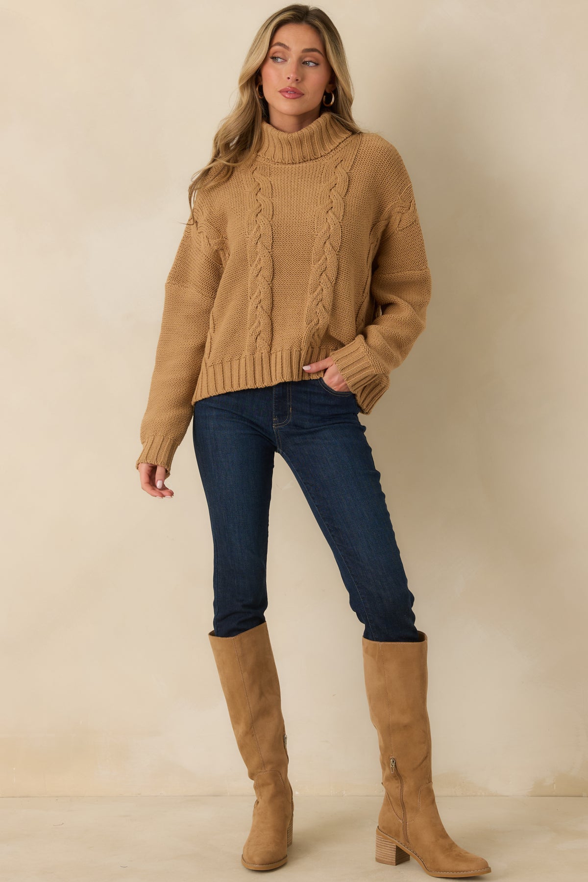 Cozy knit sweater showcasing textured cable detailing across the front, relaxed long sleeves, and a subtly shorter length.