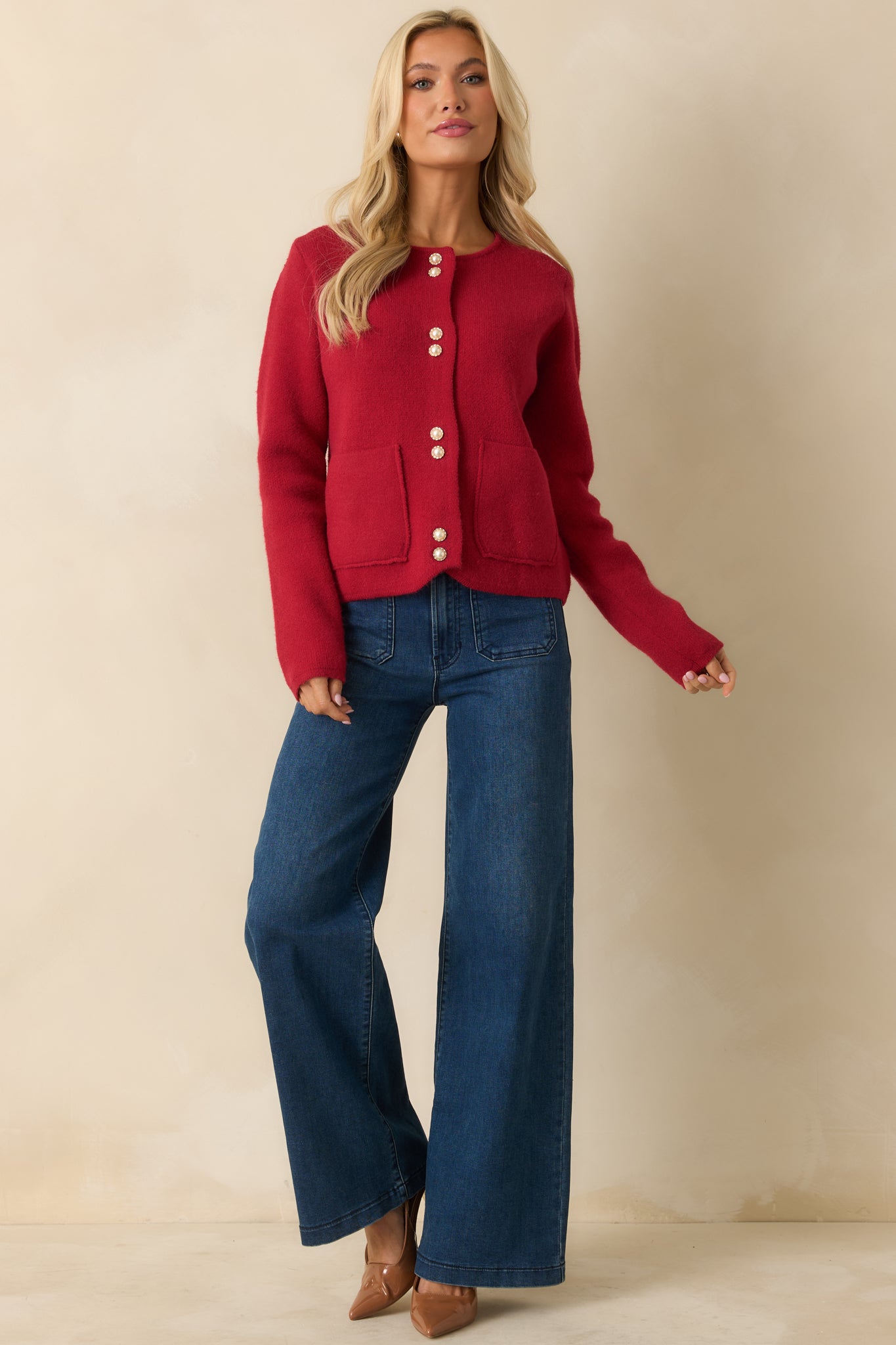 Cozy red knit cardigan with front patch pockets, pearl-button closure, and a relaxed, long-sleeve fit.