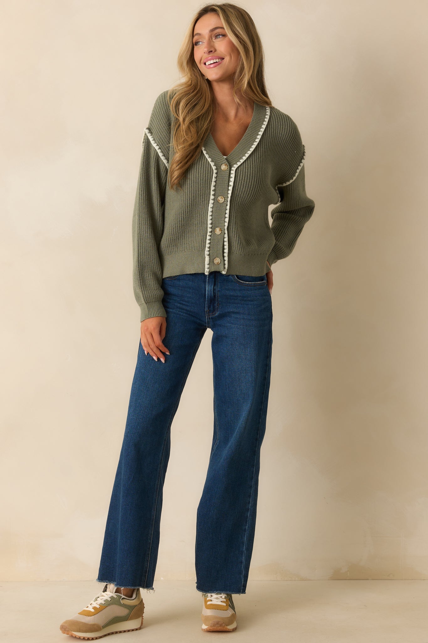 Cozy v-neck cardigan in sage green with long sleeves and decorative whipstitch accents.