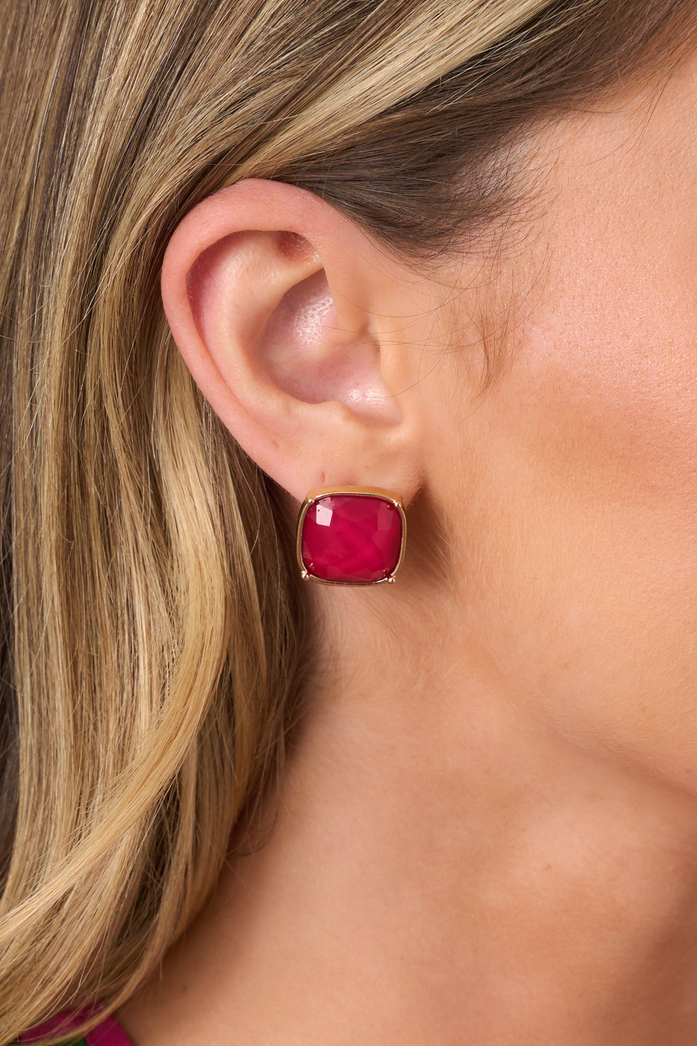 Close-up of the faceted cranberry red stone and polished gold-tone frame, highlighting the dimensional sparkle and refined setting.