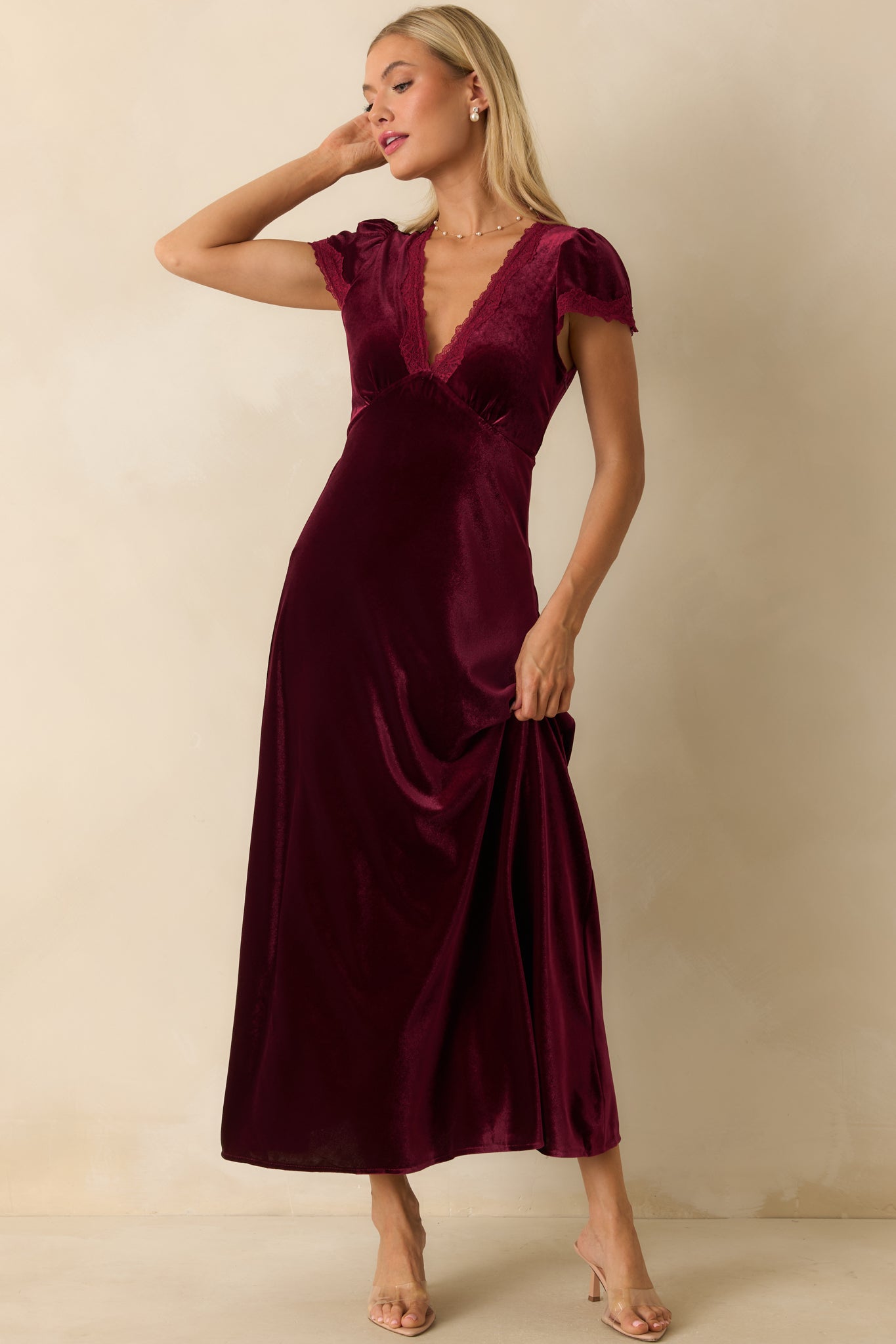 Floor-length cranberry red velvet maxi dress showcasing flutter sleeves, V-neckline with lace trim, and relaxed A-line silhouette.
