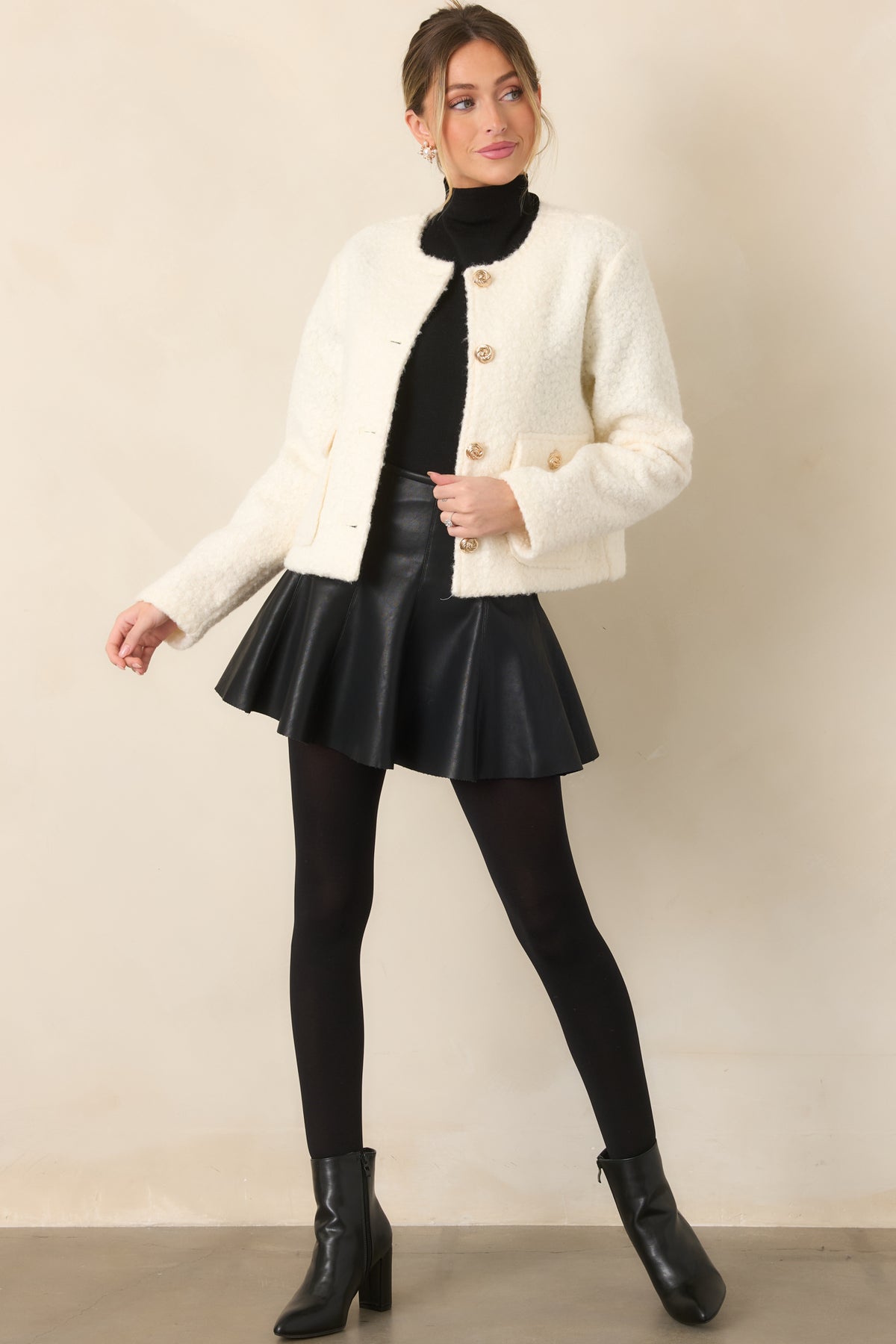 Textured cream bouclé jacket with a classic round neckline, long sleeves, and polished gold button closures.