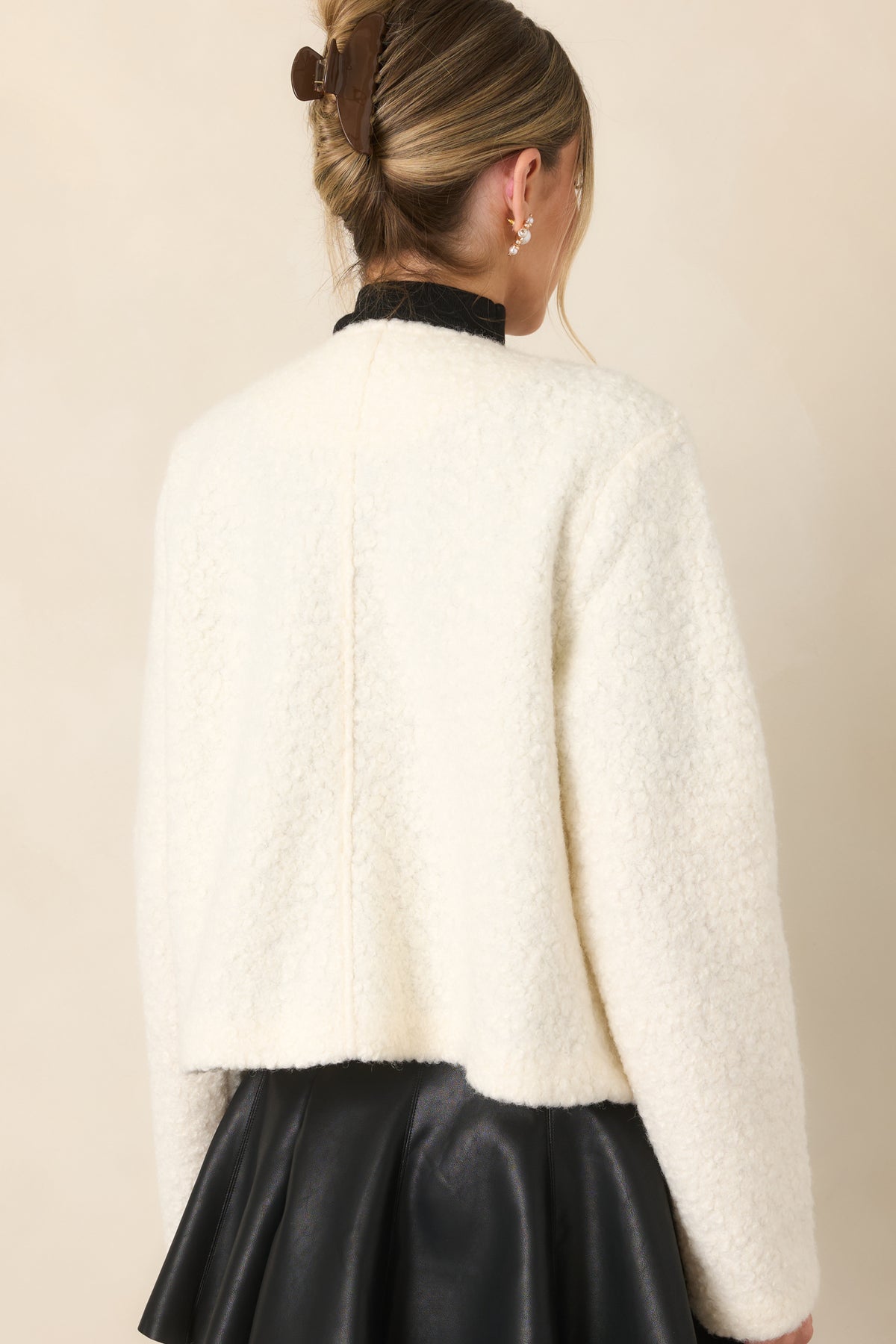 Rear view of the cream bouclé jacket showing its clean silhouette and long sleeves.