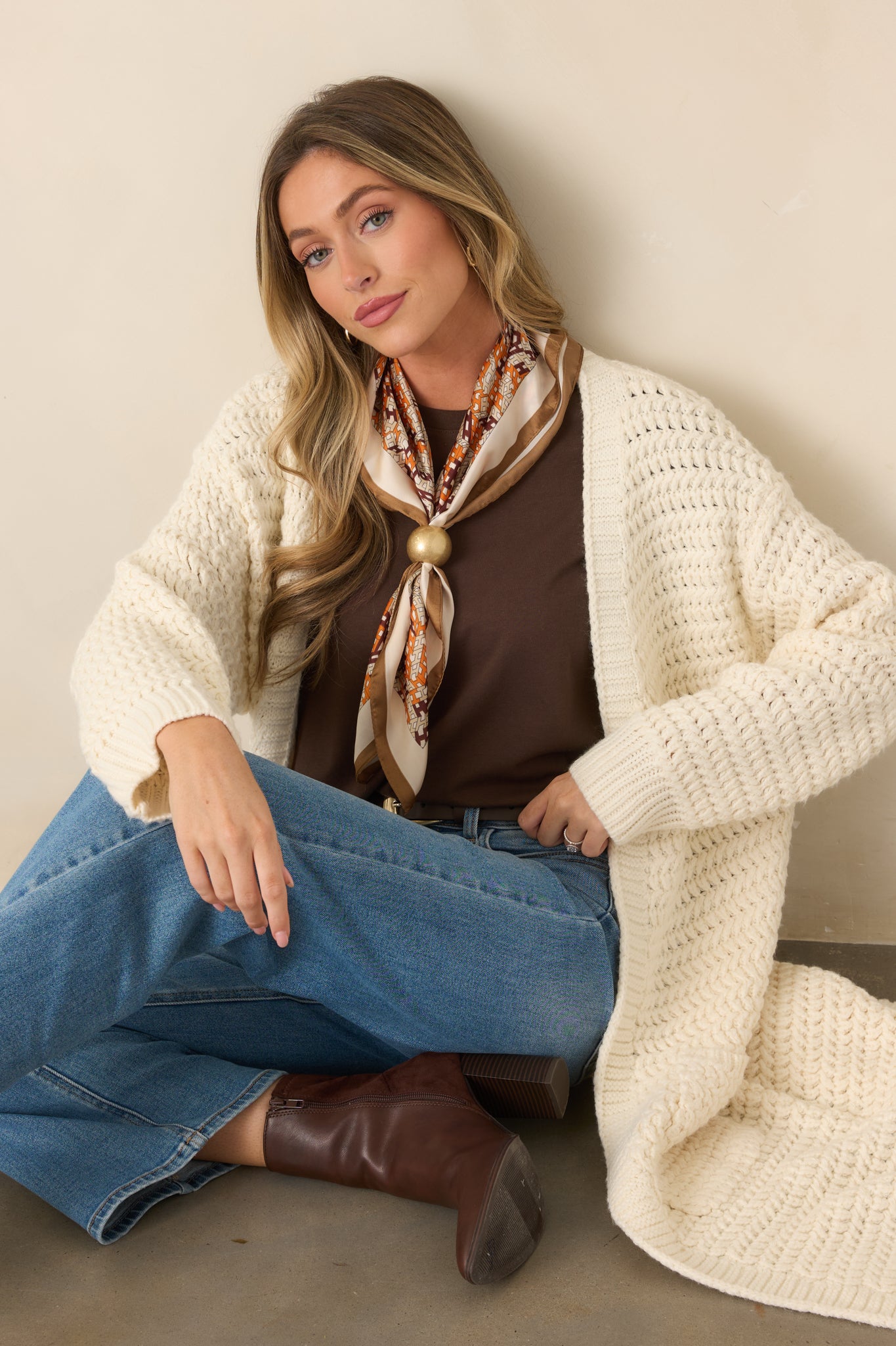 Close view of the cream cardigan highlighting its chunky knit texture and open-front construction.