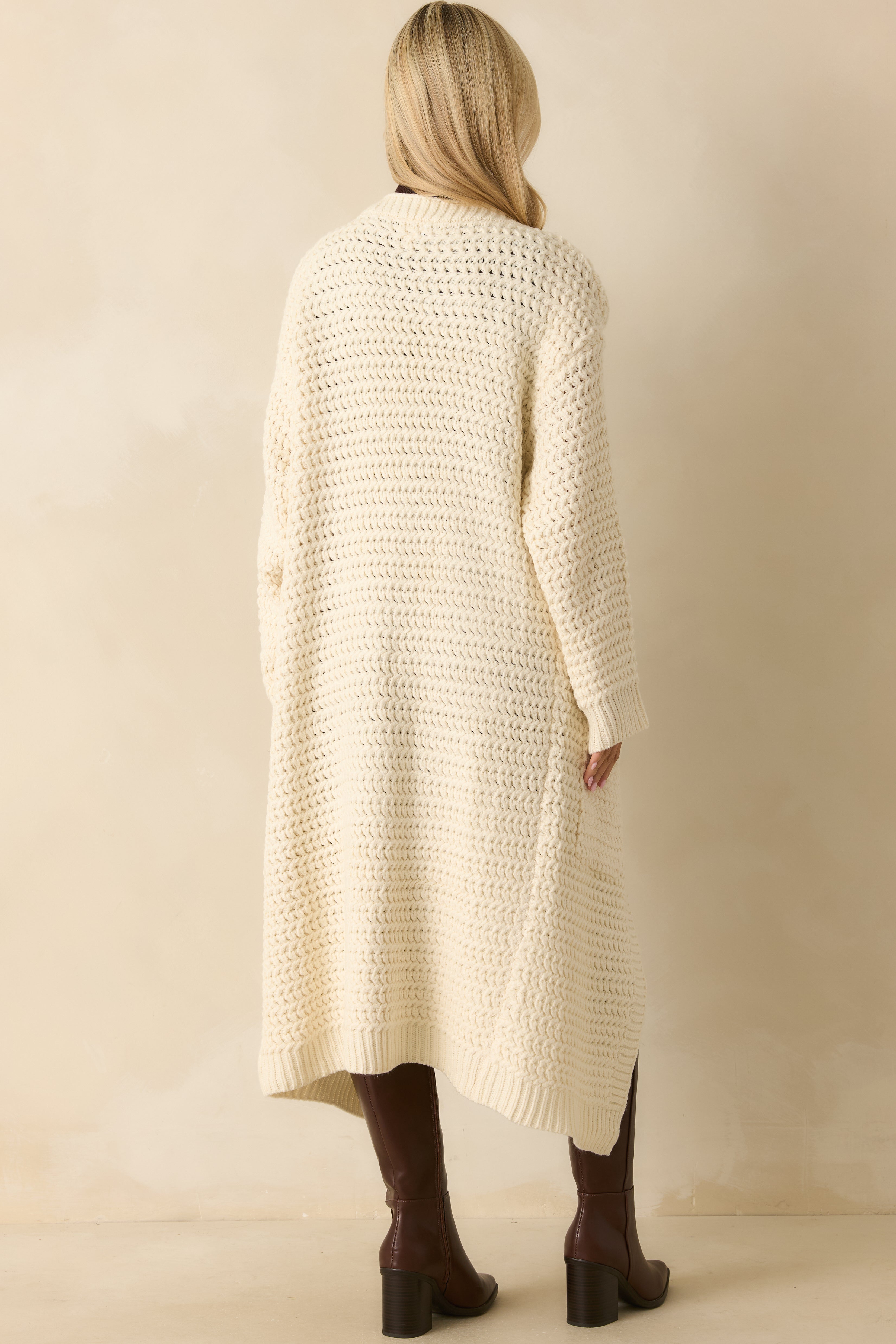 Rear view of the cream duster cardigan highlighting the longline silhouette and relaxed knit construction