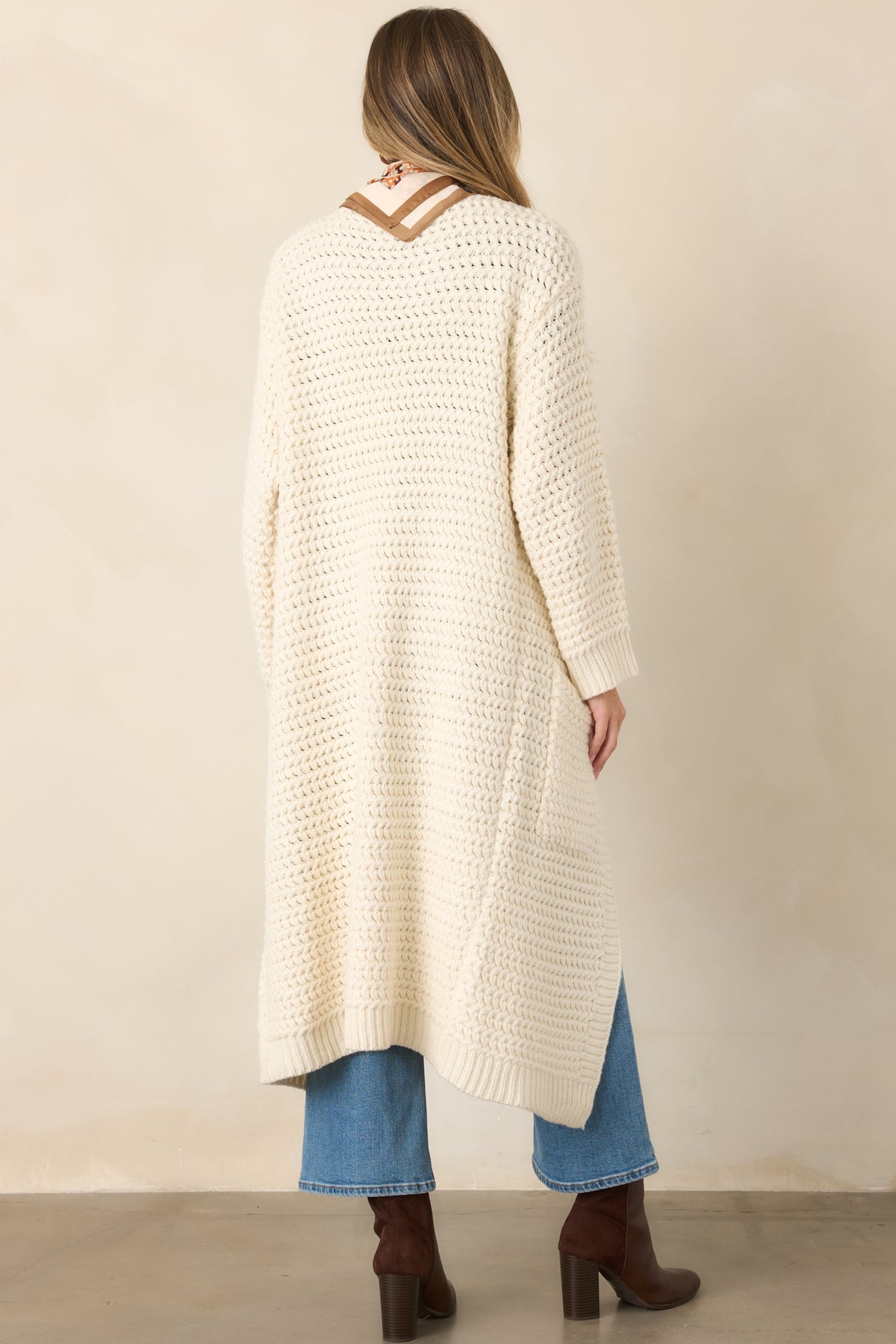 Rear view of the cream duster cardigan showcasing its relaxed longline silhouette and chunky textured knit construction.