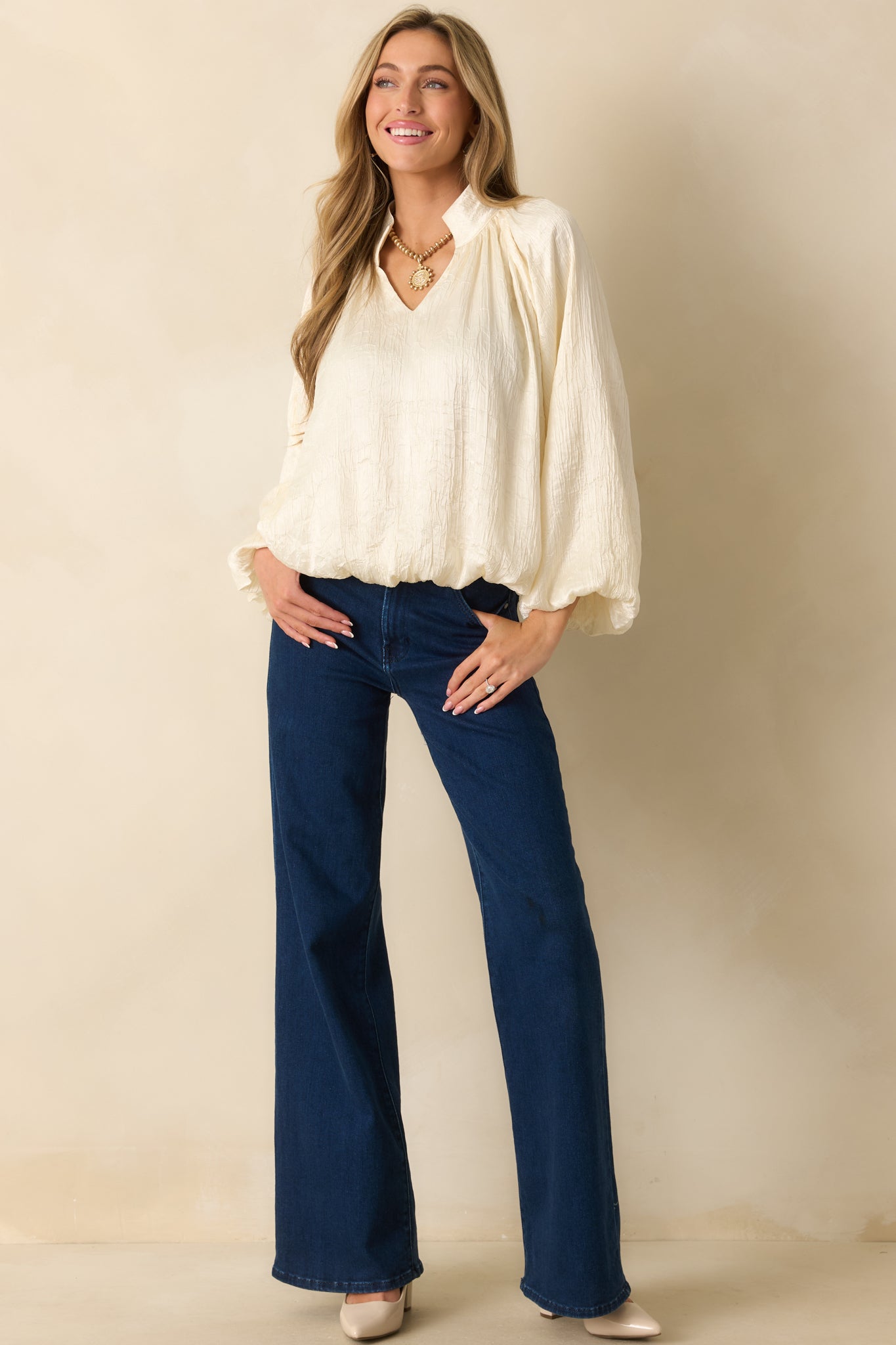 Relaxed-fit cream satin top with subtle textured fabric, V-neckline, and billowy peasant sleeves.