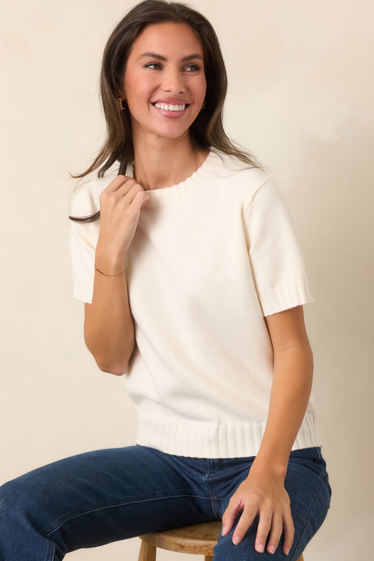Creamy ivory knit top designed with a relaxed shape, short sleeves, and textured ribbed trim around the neckline, cuffs, and hem.