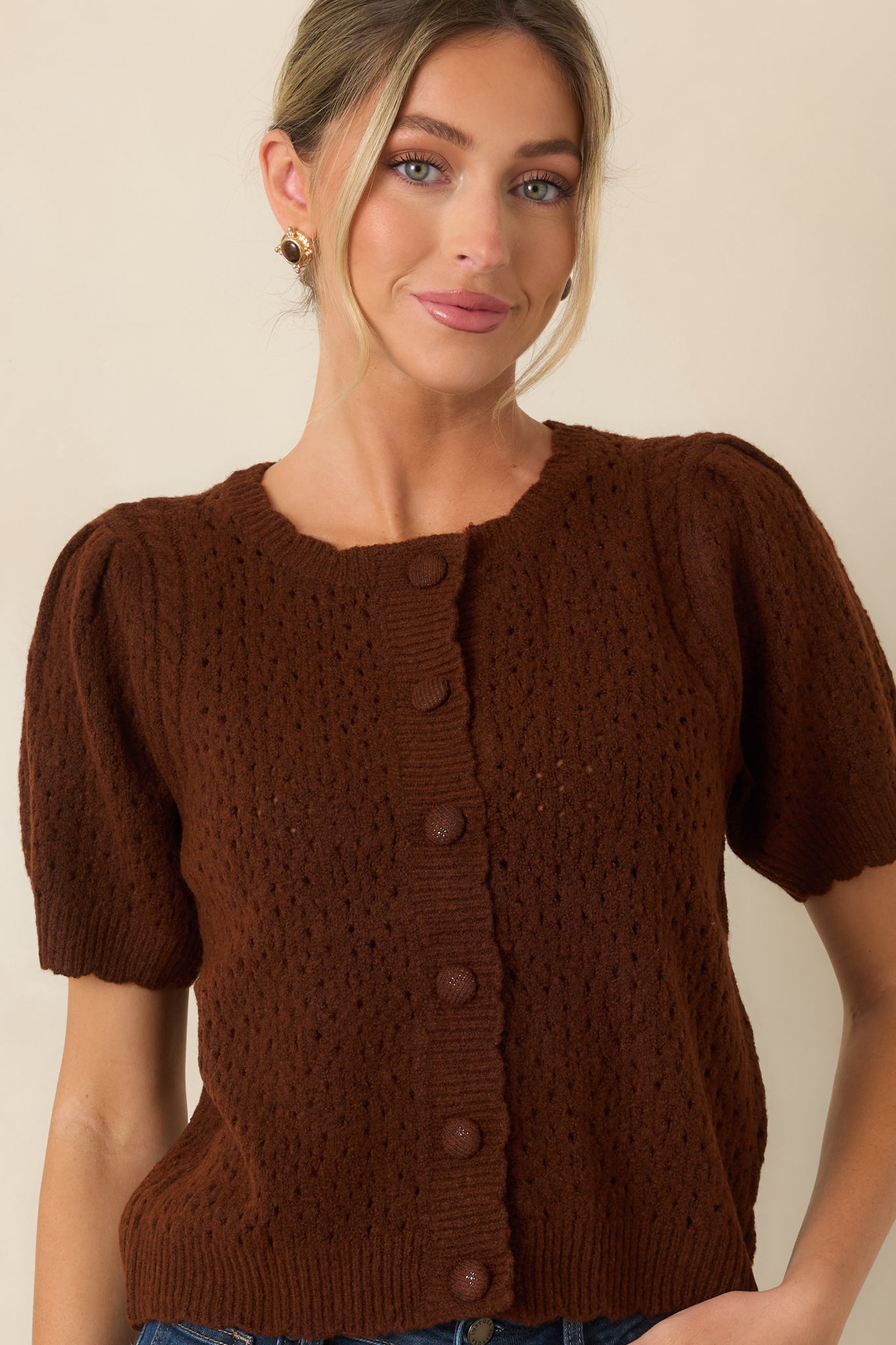 Close view of the cardigan featuring the crew neckline, fabric-covered buttons, and intricate pointelle knit texture.