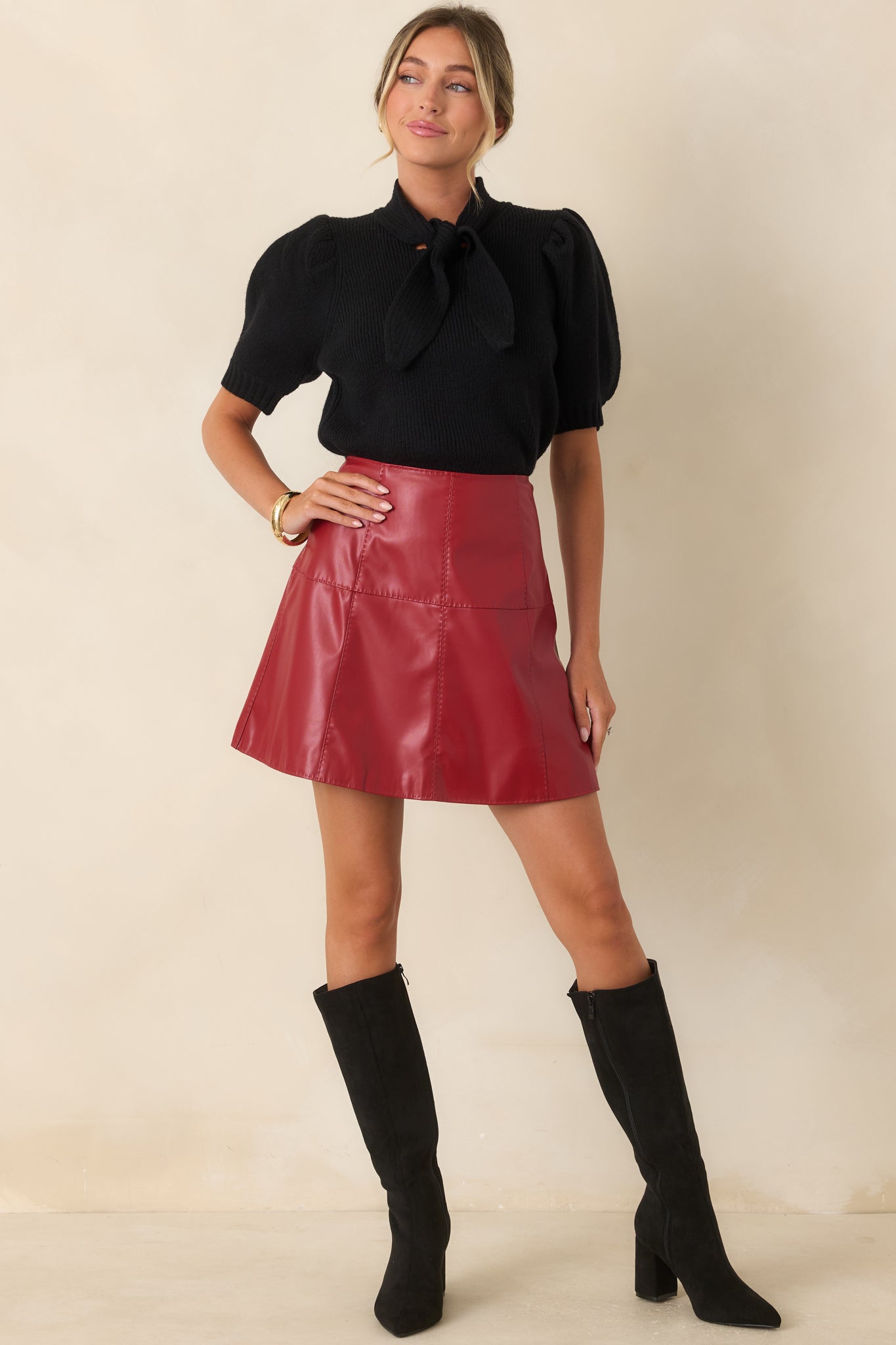 Crimson red faux leather mini skirt featuring a high-rise waist, paneled seaming, A-line silhouette, and concealed back zipper.
