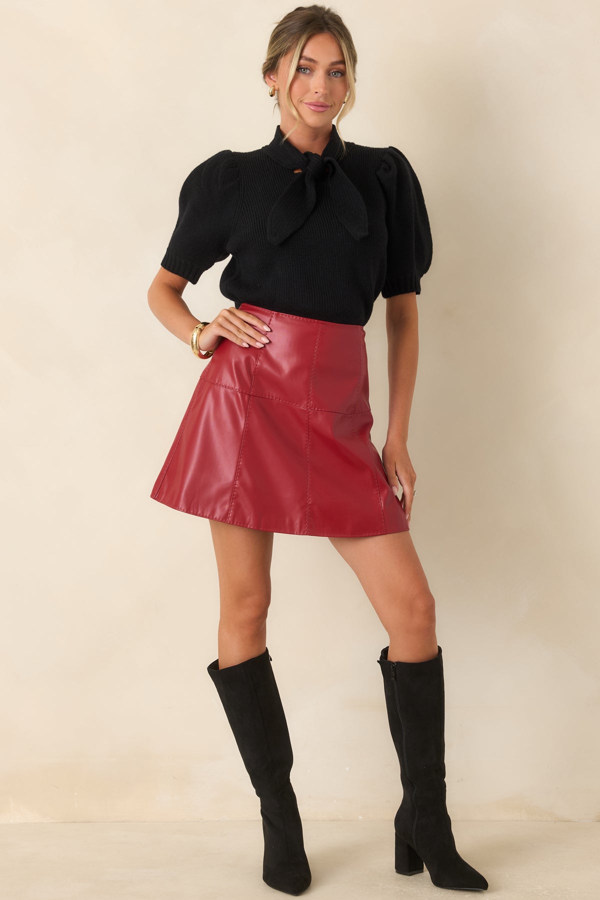 Crimson mini skirt showcasing the smooth faux leather texture, flattering high-rise fit, and tailored panel construction.