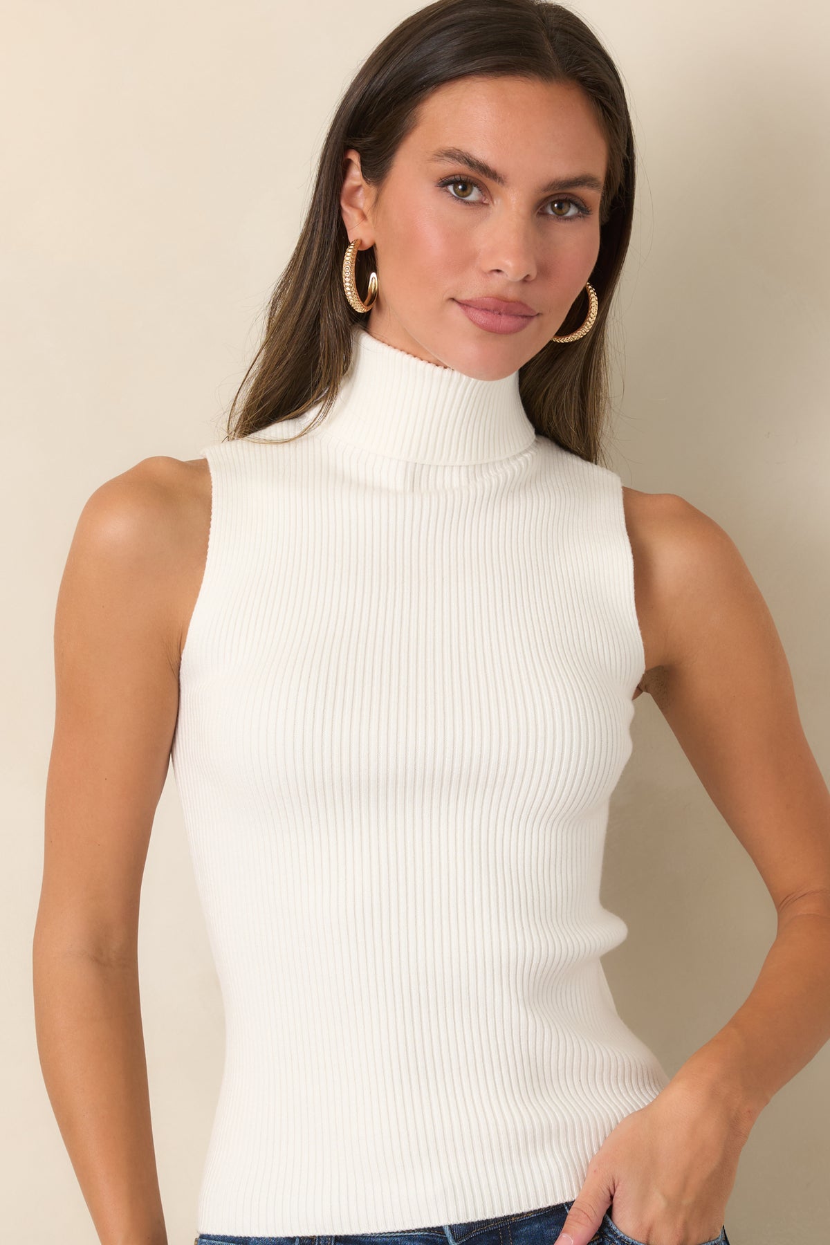 Crisp ivory knit top featuring a soft fold-over turtleneck and streamlined shape.