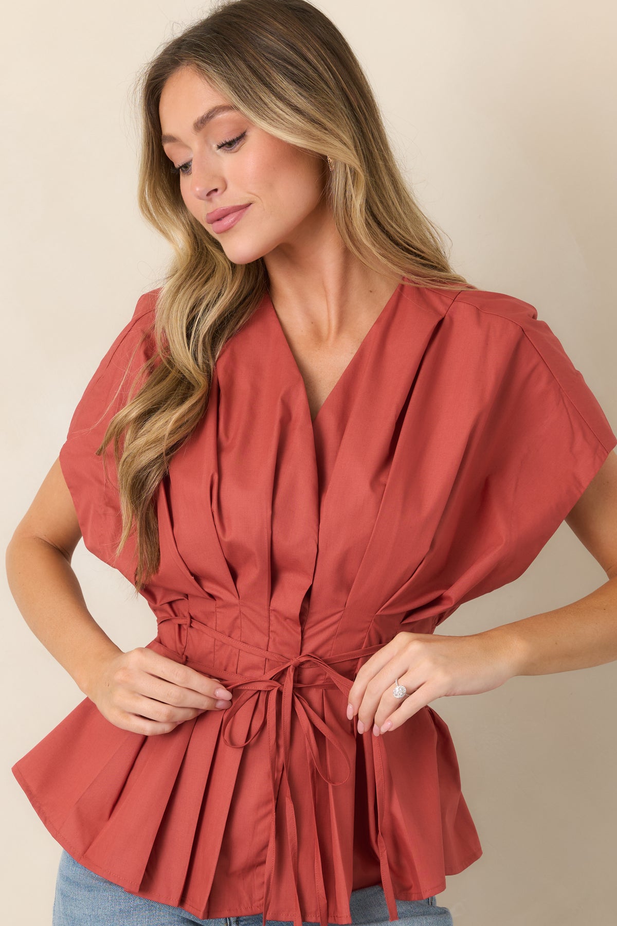 Top featuring crisp pleats extending from the V-neckline through the bodice, paired with dramatic short sleeves.