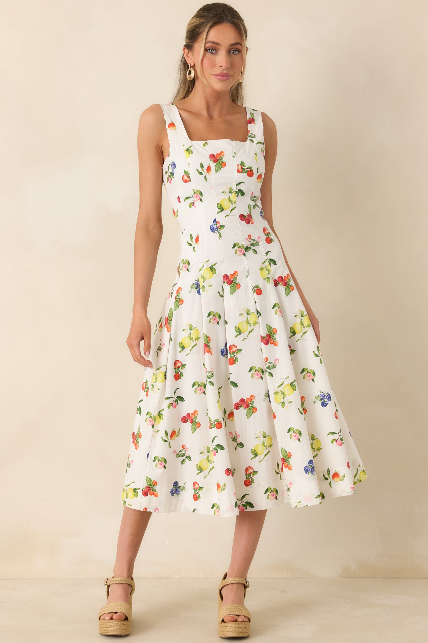 Crisp white midi dress adorned with multicolor fruit motifs, fitted bodice, and gentle pleats